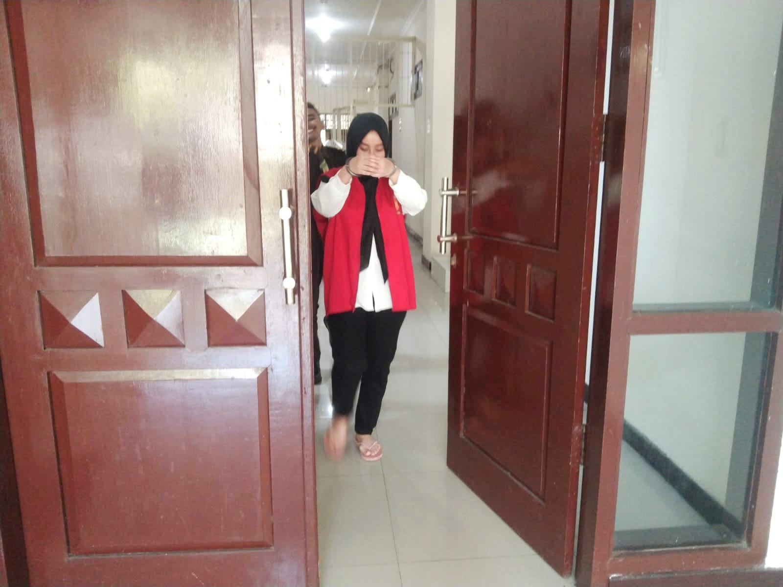 TERTUNDUK MALU : Terdakwa Belinda Anastasha Putri menunduk dan menutup wajahnya usai menjalani sidang di PN Gresik.