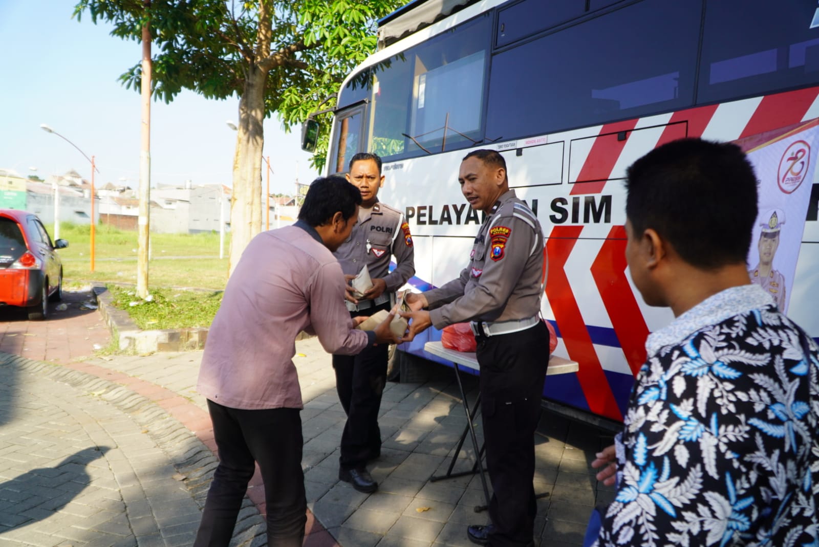 SARAPAN GRATIS: Anggota Satlantas Polres Gresik membagikan sarapan gratis ke para pemohon SIM keliling di Kabupaten Gresik.