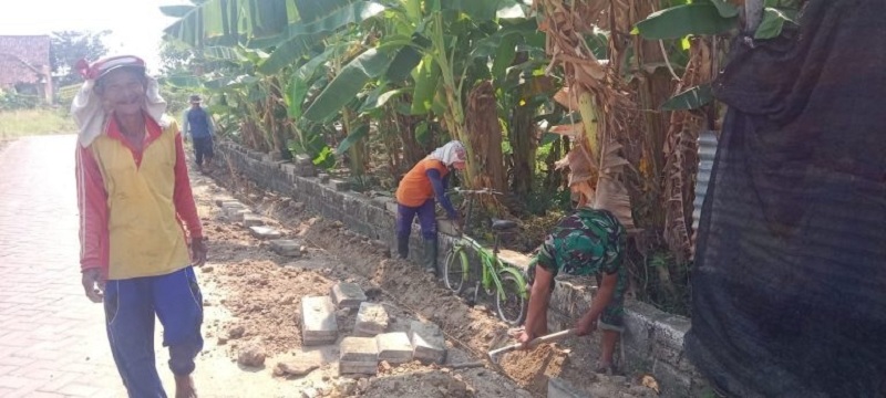 GOTONG ROYONG: Anggota Koramil Balongpanggang Gresik, warga bergotong royong memperbaiki jalan paving dan saluran air bersama warga Desa Wotansari, Kecamatan Balongpanggang.