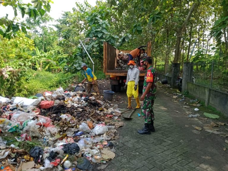 BERSIHKAN SAMPAH: Anggota Koramil Bungah Serda Puguh membantu warga dan petugas kebersihan membersihkan tumpukan sampah yang menumpuk di TPS Lingkungan Desa Mojopurowetan Kecamatan Bungah, Gresik.