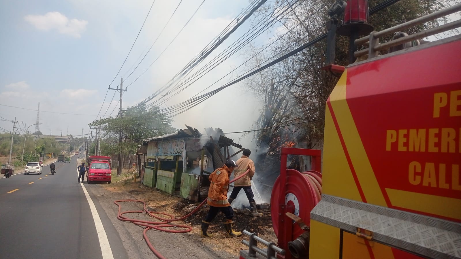 PEMBASAHAN: Petugas Damkarla Gresik melakukan pembasahan sebuah warung terbengkalai di Desa Kedamean, Kecamatan Kedamean, Gresik.
