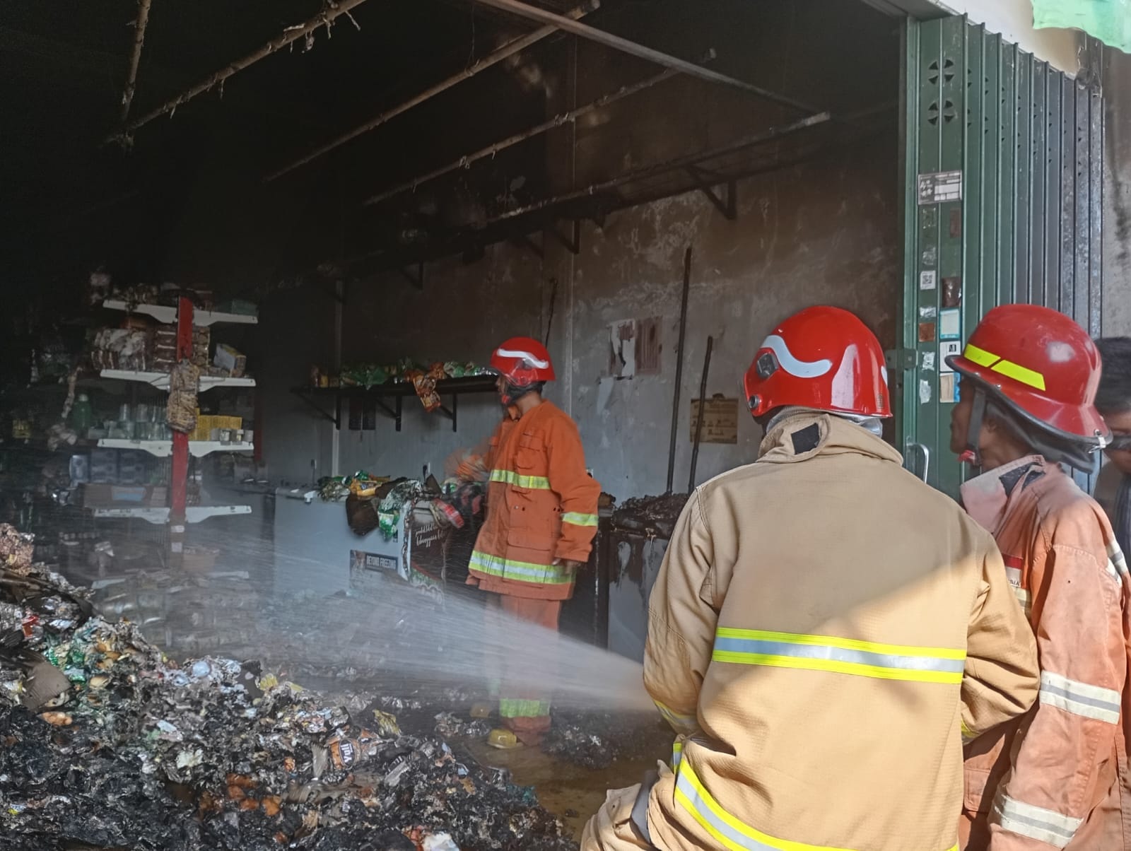 PEMADAMAN: Anggota Damkarla Kabupaten Gresik saat melakukan pemadaman di Toko Budi Snack di Jalan Sidodadi, Desa Sembayat, Kecamatan Manyar, Kabupaten Gresik.
