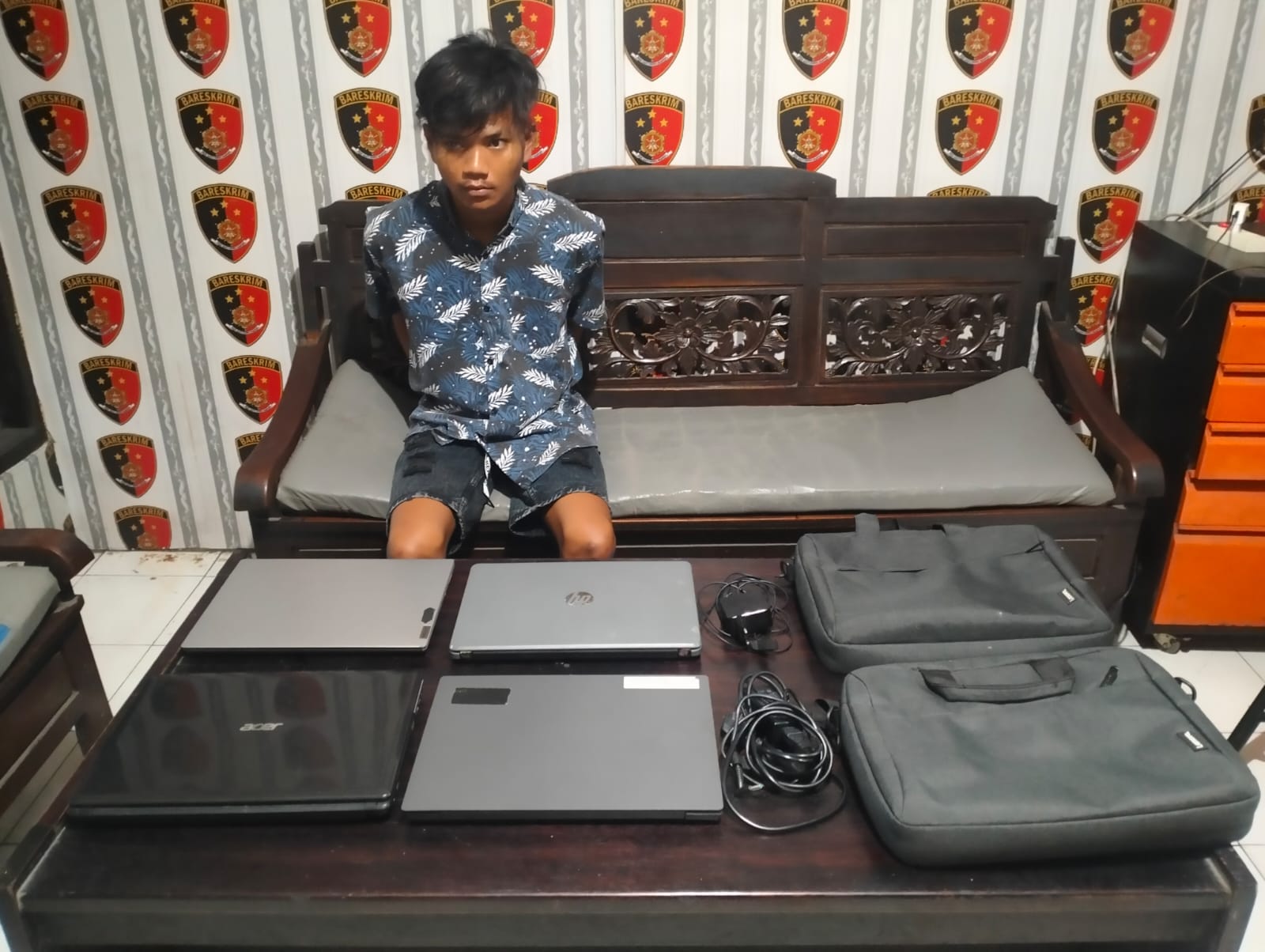 DIAMANKAN : Tersangka Achmad Revly Andrew Hehanusa saat diamankan anggota Reskrim Polsek Cerme beserta barang bukti  empat buah laptop di Mapolsek Cerme, Gresik.