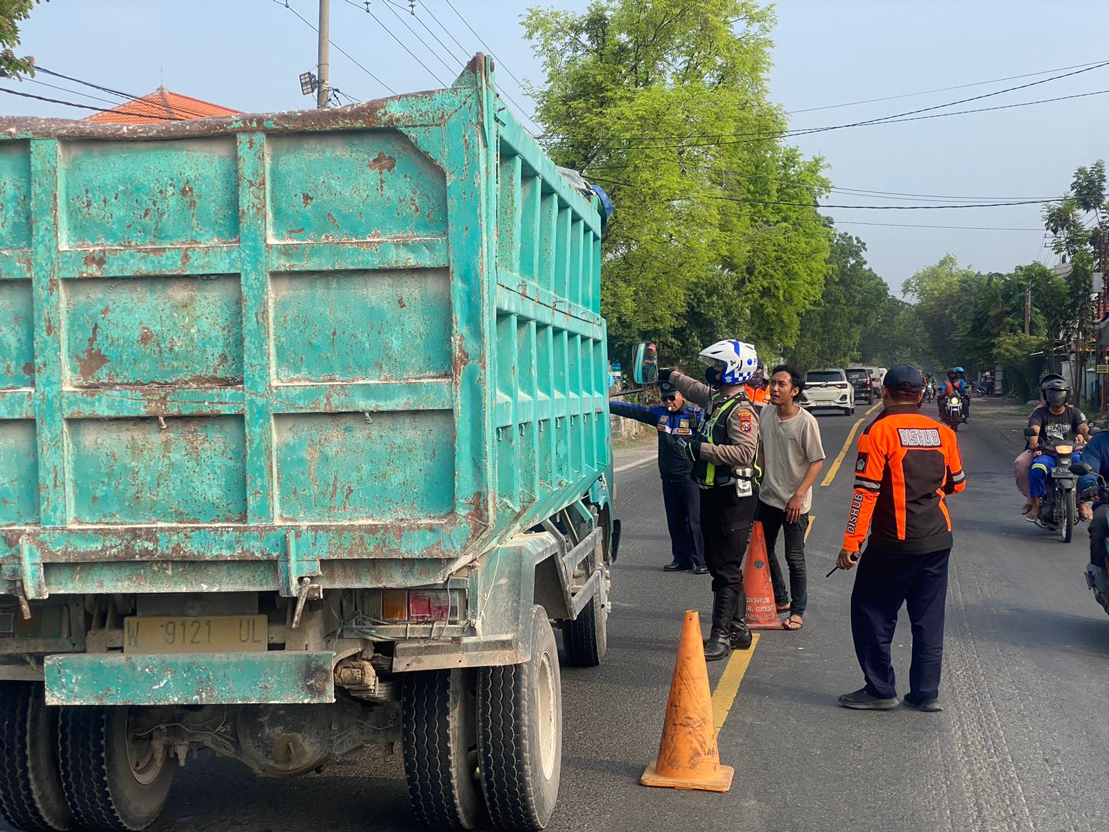 DITILANG : Anggota Satlantas Polres Gresik saat melakukan razia dan penindakan penilangan kepada kendaraan truk galian C yang melanggar jam operasional di Desa Ngawen, Kecamatan Sidayu, Gresik.