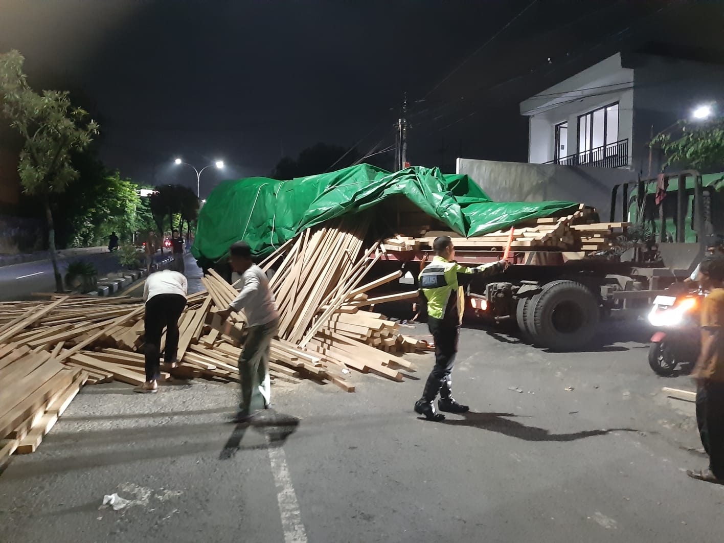 TUMPAH : Truk trailer bermuatan kayu tumpah di Jalan Raya Gending Wetan, Singosari, Kecamatan Kebomas, Gresik.
