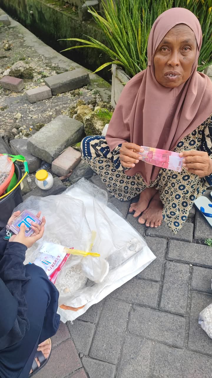 UANG PALSU: Seorang penjual makanan memperlihatkan uang pecahan seratus ribu yang diduga palsu dari pembelinya di dekat pintu gerbang Perum Pondok Permata Suci (PPS), Desa Suci, Manyar, Gresik.