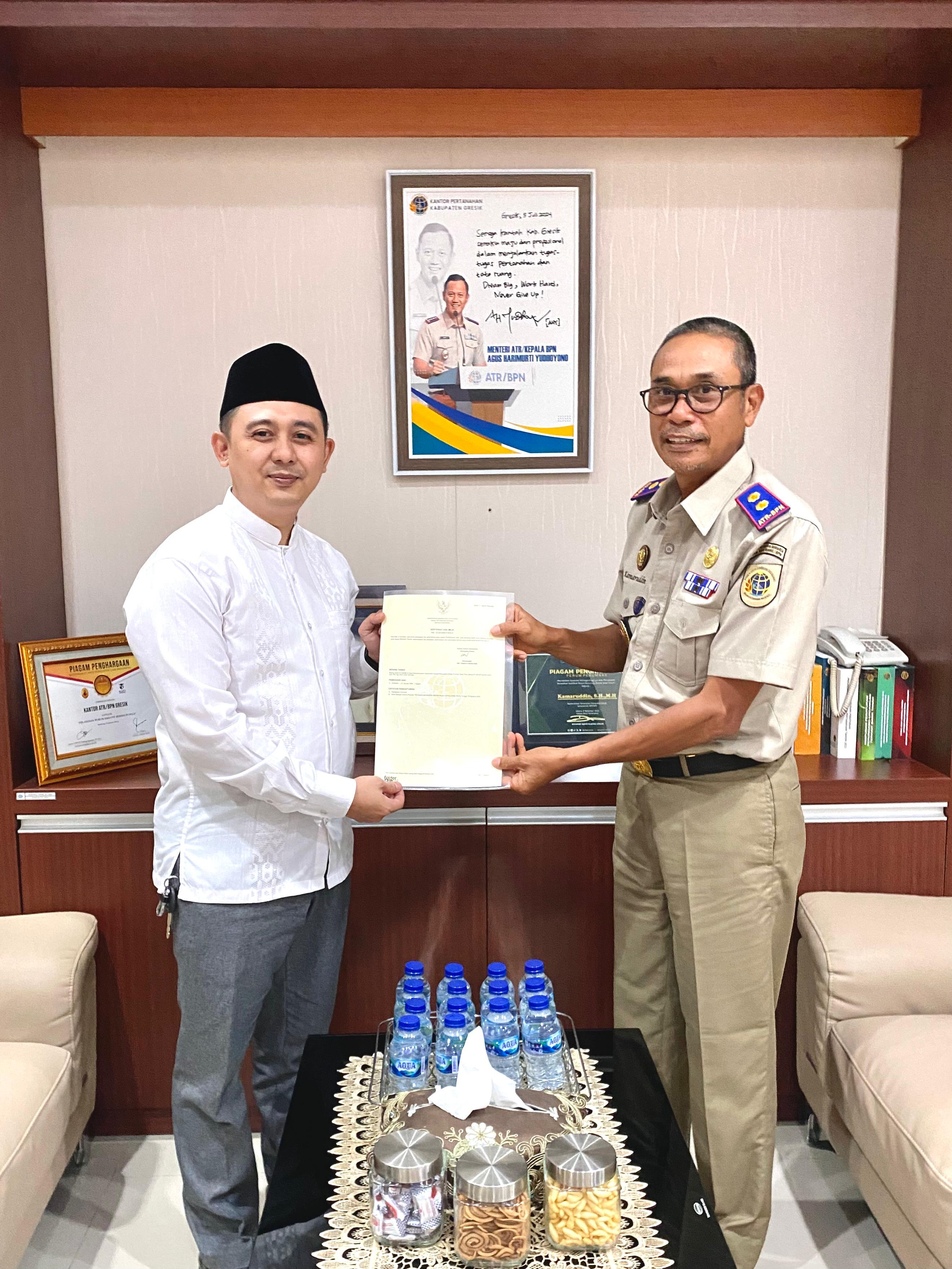 Wakil Rektor Unhasy Tebuireng Jombang, Abdullah Aminuddin menerima sertipikat pengganti dari Kepala Kantor ATR/BPN Gresik, Kamaruddin.