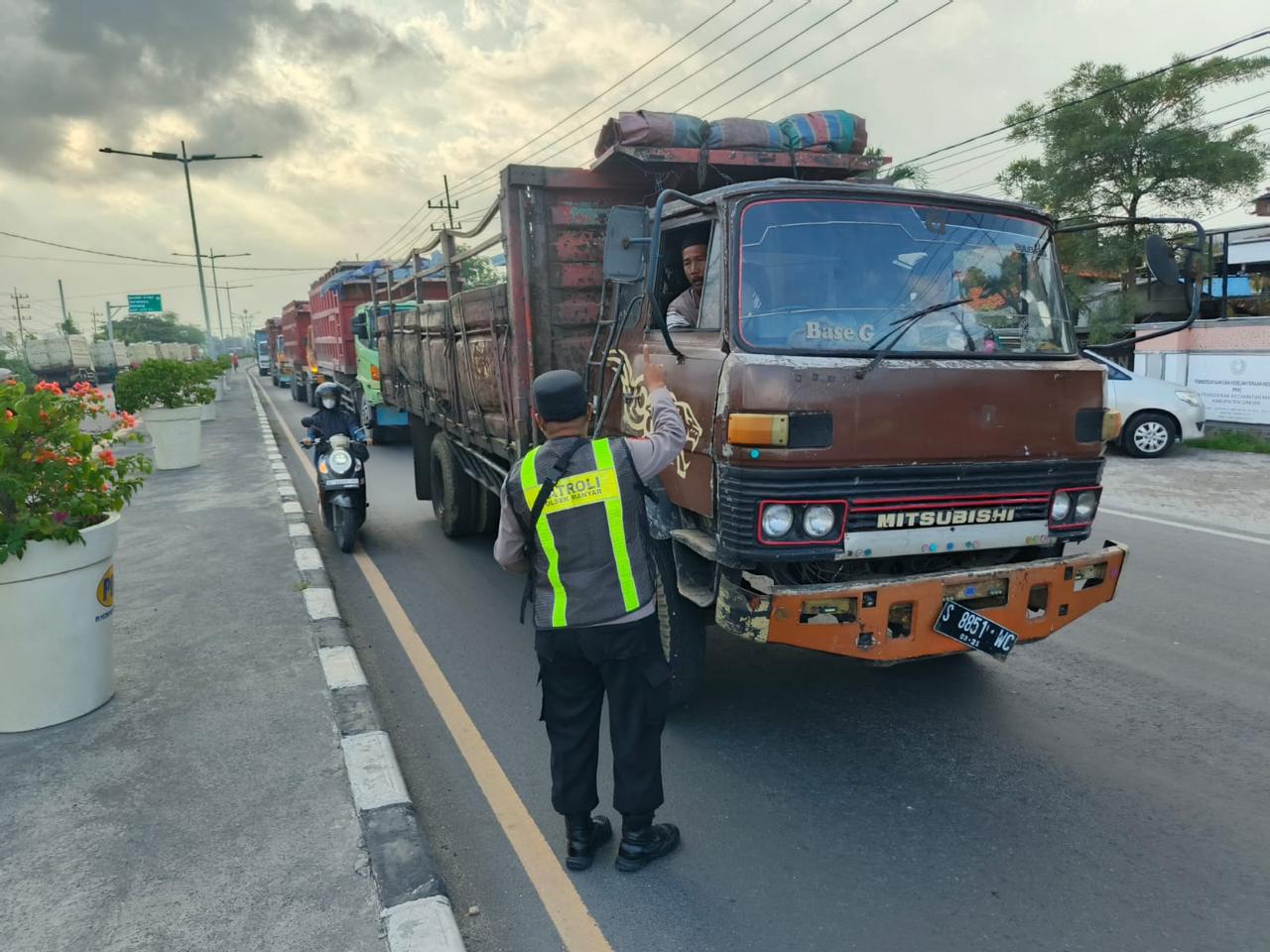 BERI TEGURAN: Anggota Polsek Manyar saat melaksanakan giat Commander Wish berupa pengamanan dan pengaturan jam operasional kendaraan angkutan barang.
