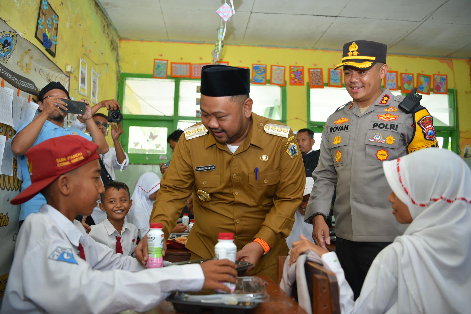 DUKUNG PRESIDEN: Kapolres Gresik AKBP Rovan Richard dan Bupati Fandi Akhmad Yani bagikan makan bergizi Gratis di SDN-71 Cerme.