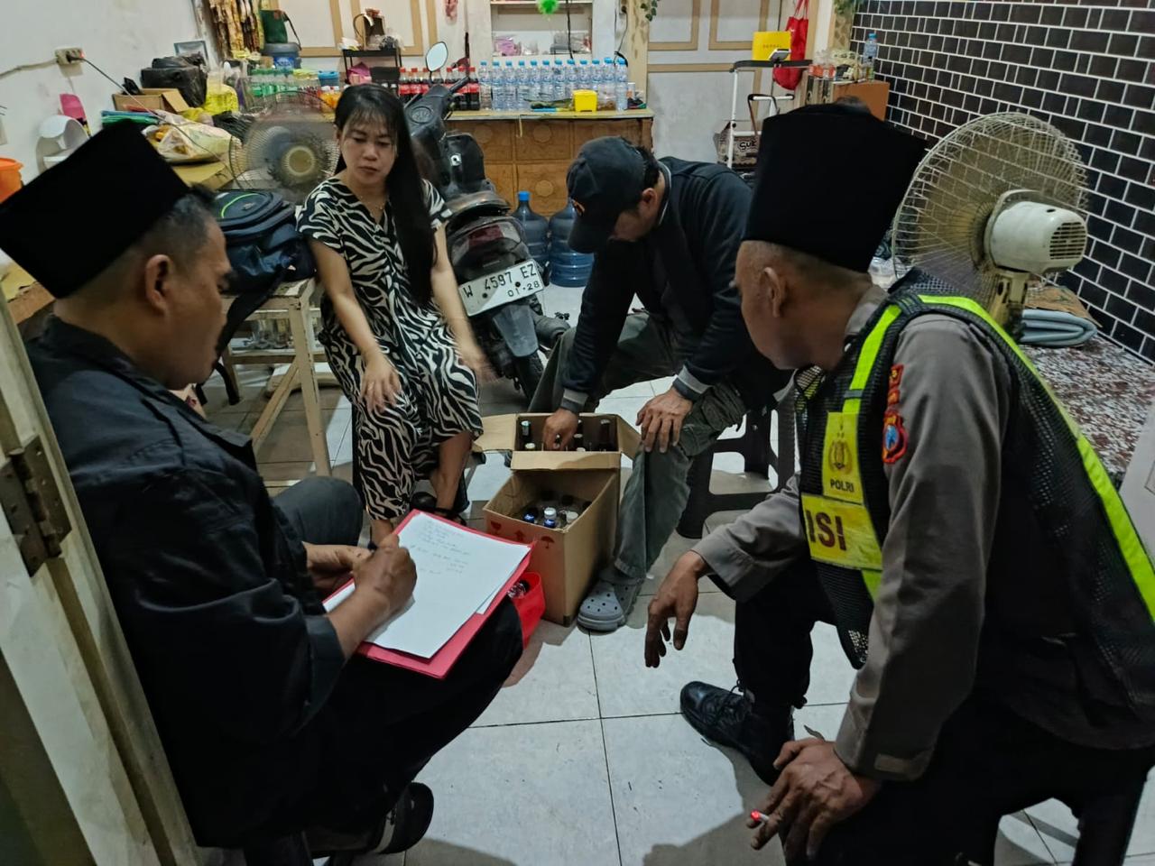 DIRAZIA: Anggota Polsek Manyar saat menggelar razia di sejumlah warkop dan menyita puluhan botol miras ilegal.