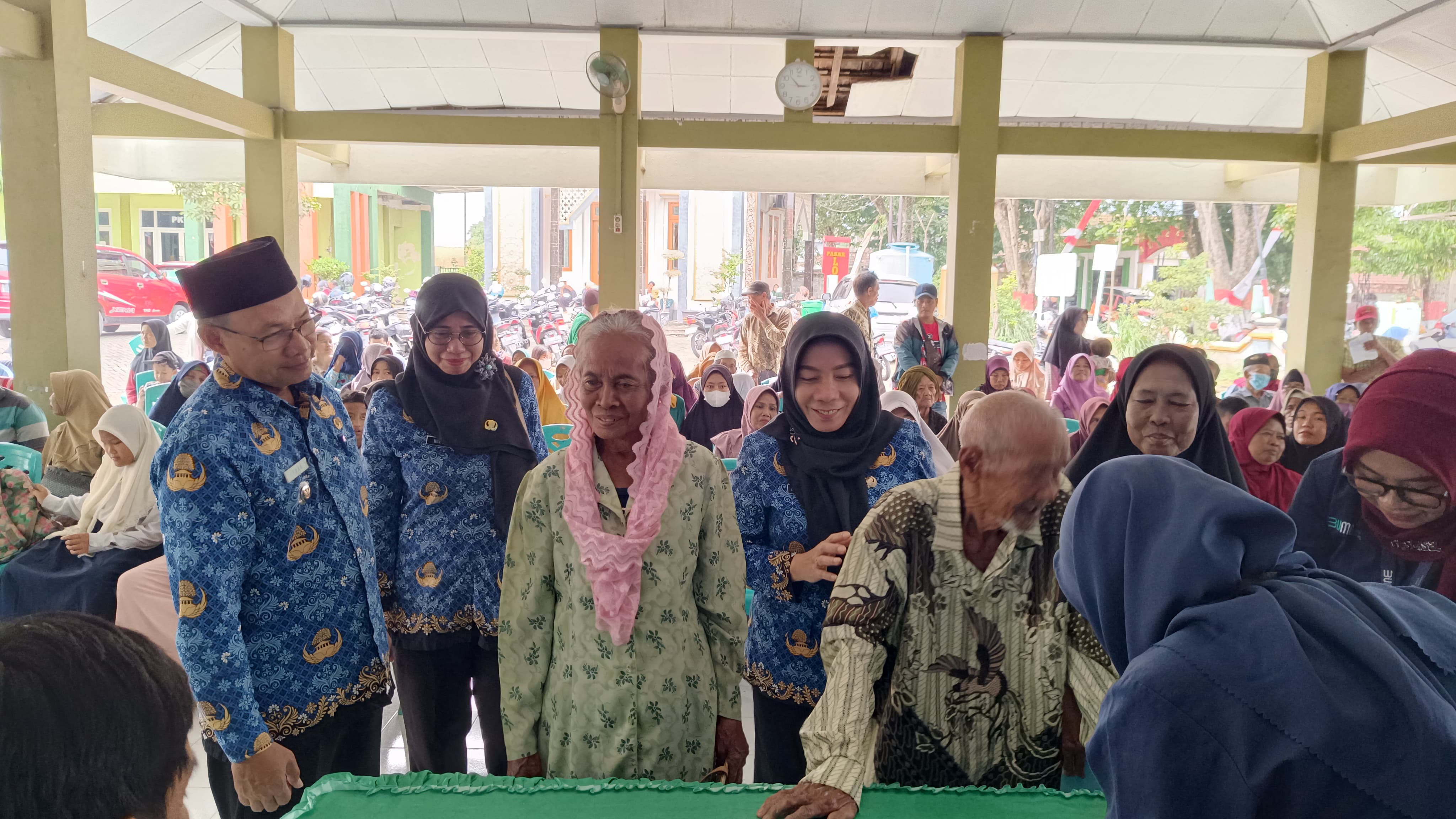BANTUAN: Kepala Dinas Sosial Kabupaten Gresik, Ummi Khoiroh memantau penyaluran bansos PKH inklusif dan santunan kehormatan bagi marbot, guru ngaji, serta penjaga makam