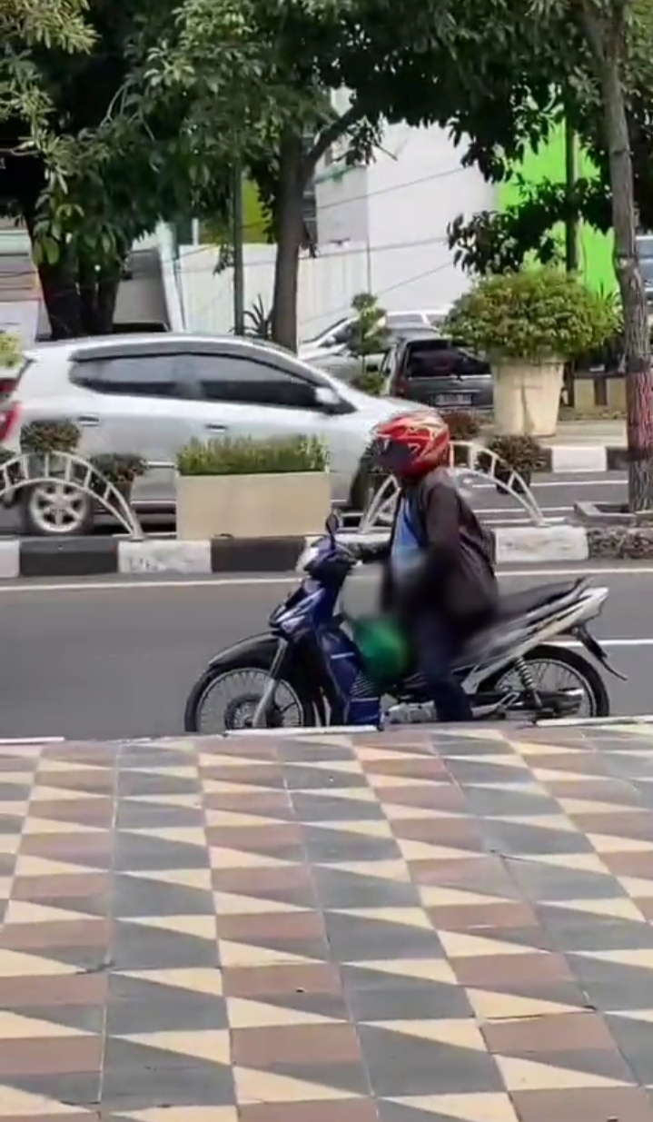 PAMER KELAMIN : Seorang pria mengendarai sepeda motor saat mengeluarkan alat kelaminnya dihadapan seorang wanita yang sedang berada di trotoar di Jalan Dr. Wahidin husodo, Kecamatan Kebomas, Gresik