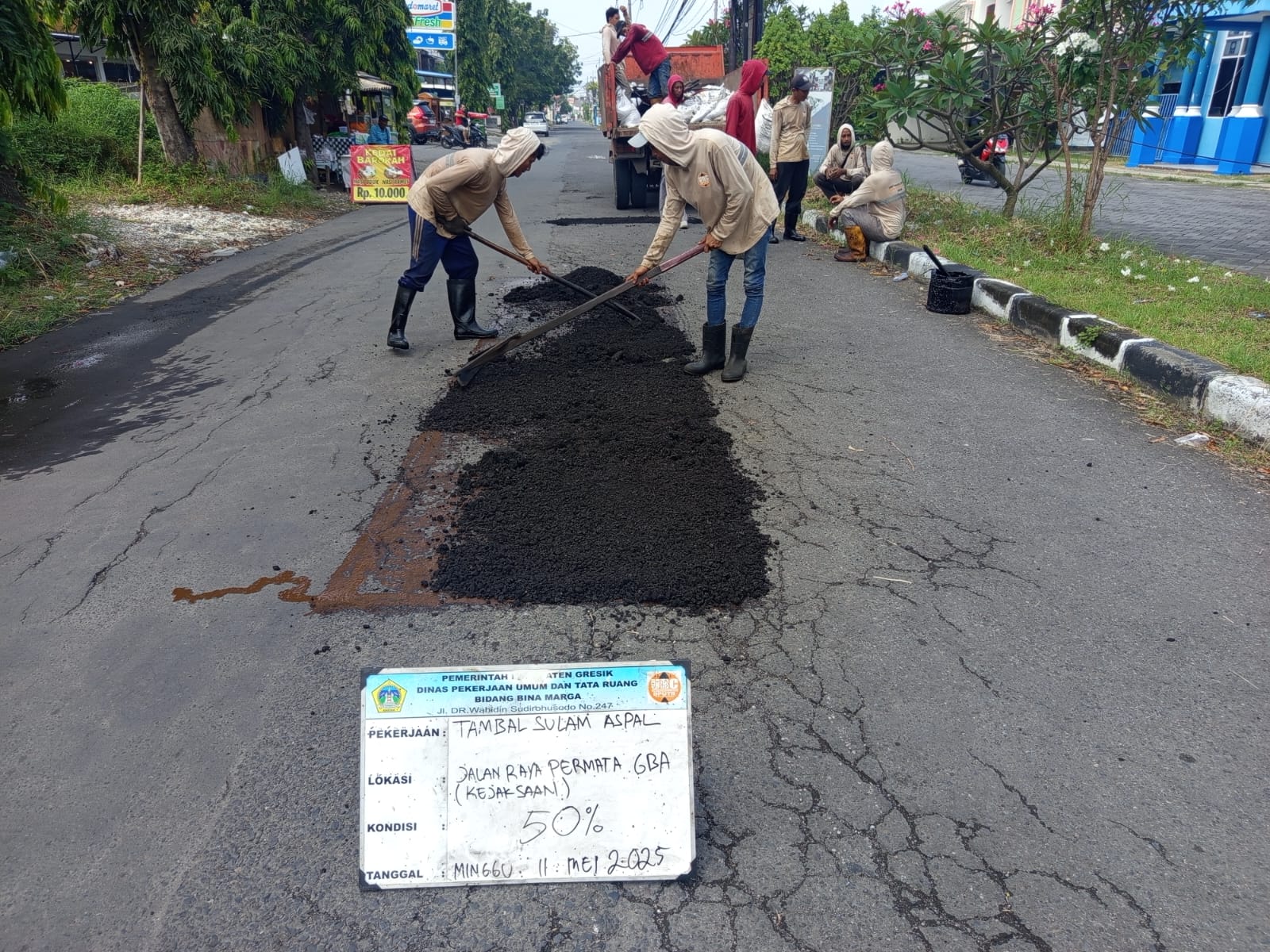 TAMBAL: Petugas Dinas Pekerjaan Umum dan Tata Ruang (DPUTR) Kabupaten Gresik menambal jalan berlubang akibat hujan.