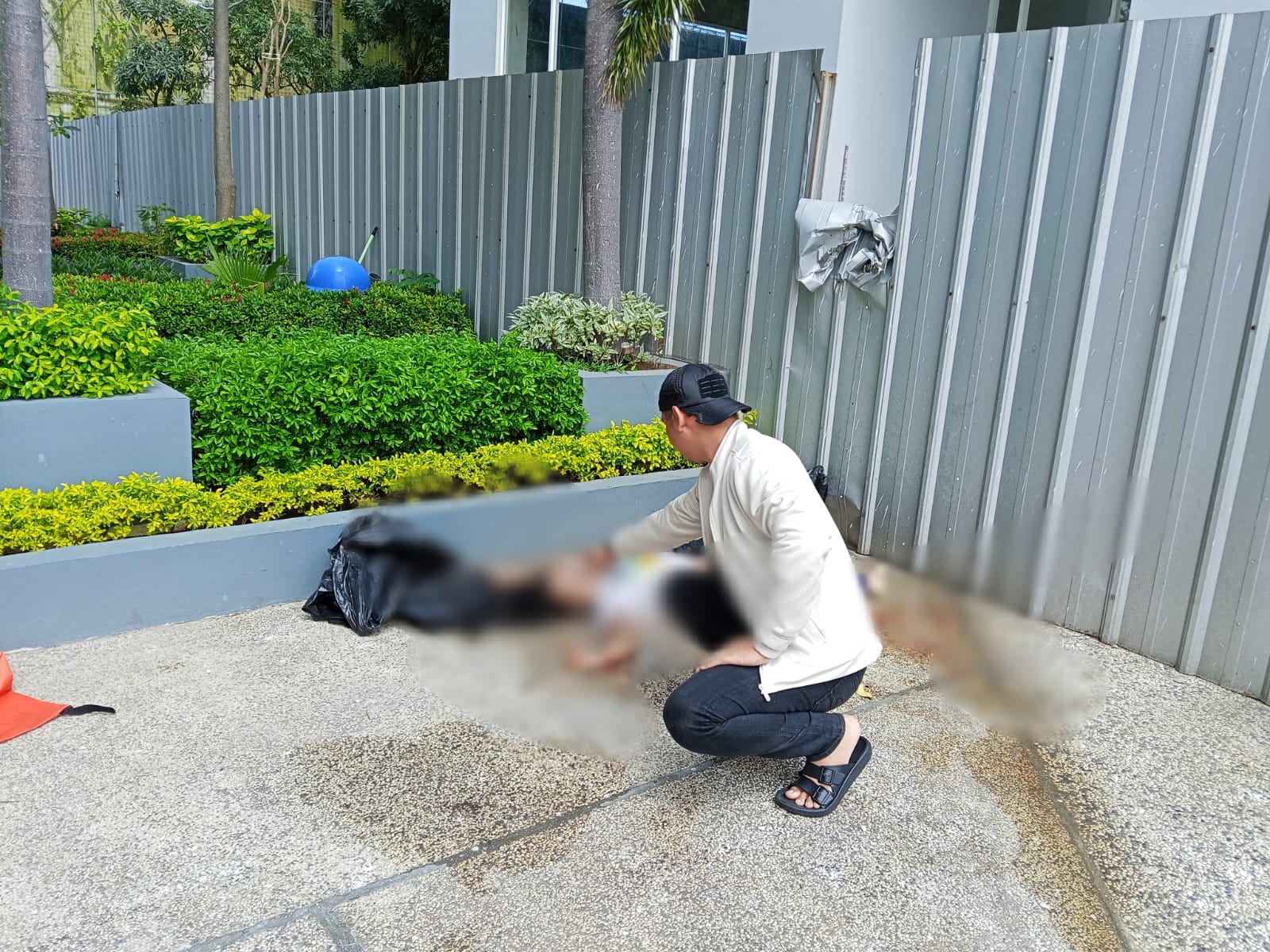 Cek Kondisi : Seorang anggota polisi memastikan kondisi korban usai lompat dari lantai 30 apartemen.
