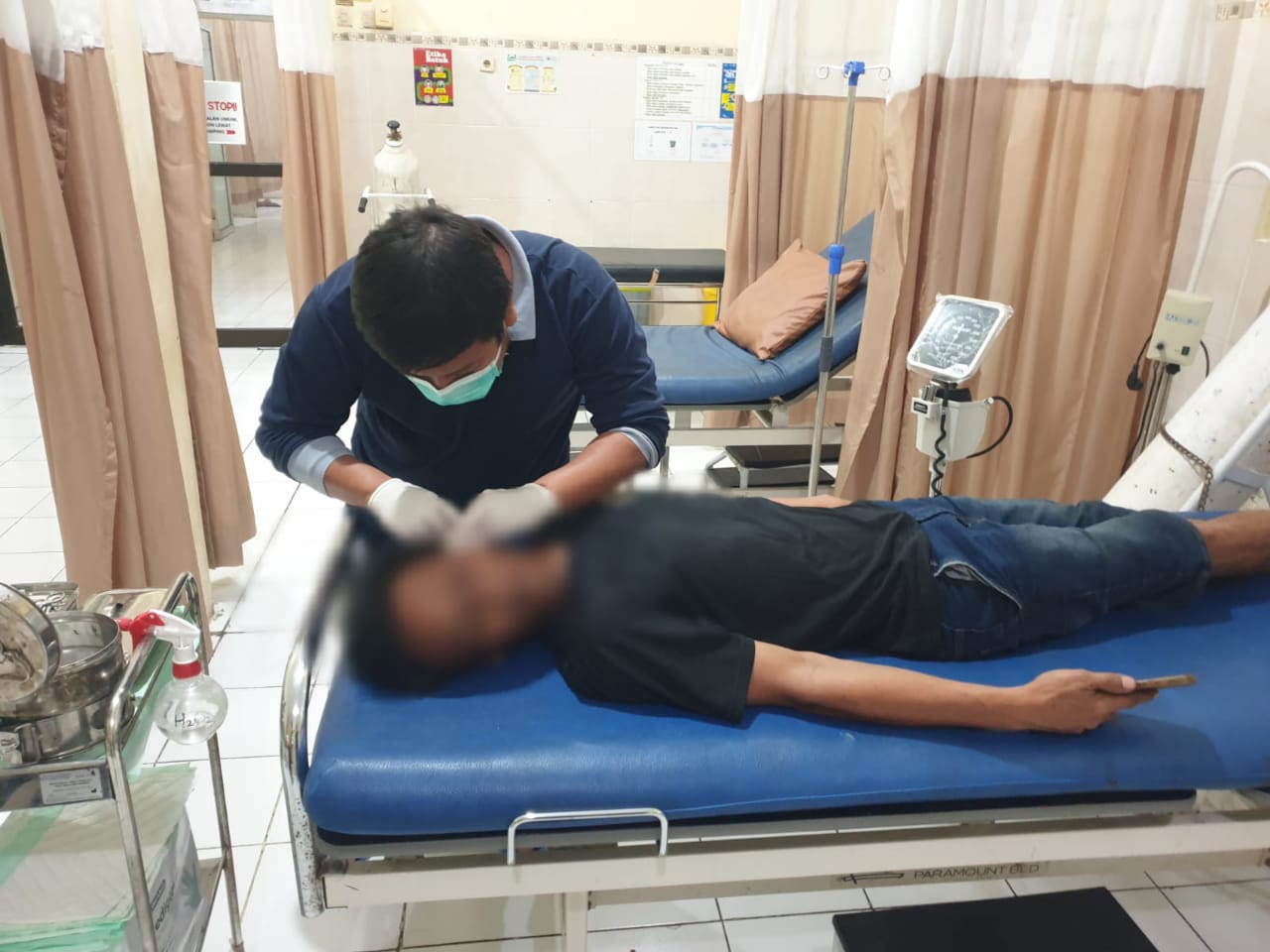 DIRAWAT : Korban Nanang saat mendapatkan perawatan medis dibantu anggota Polsek Ujungpangkah, Gresik.