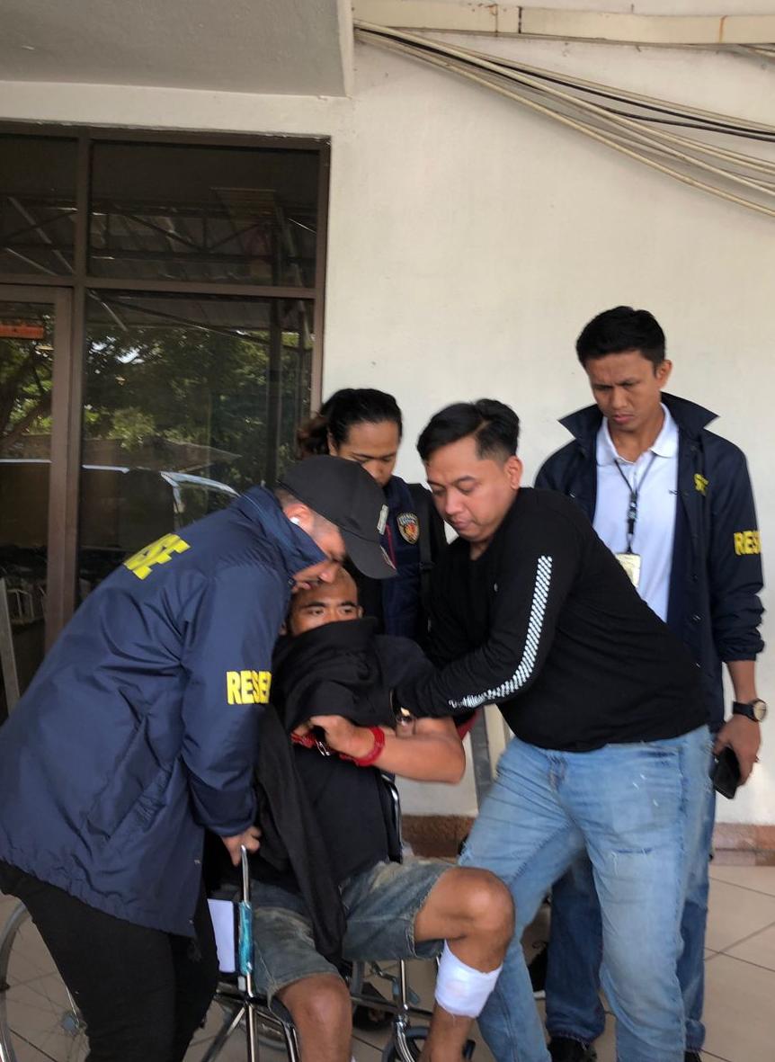 DITANGKAP: Anggota Satreskrim Polres Gresik saat menggelandang tersangka Ahmad Midhol yang terlihat ditembak kedua kakinya.