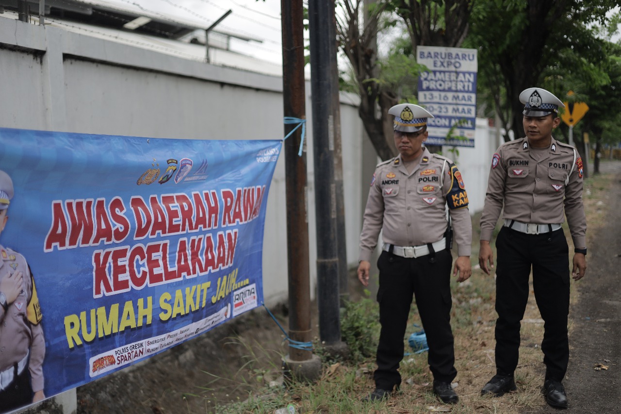 PASANG BANNER : Anggota Satlantas Polres Gresik pasang banner himbauan mengingatkan masyarakat agar berhati - hati saat berkendara di sejumlah Jalan Raya di Gresik yang dianggap rawan kecelakaan.