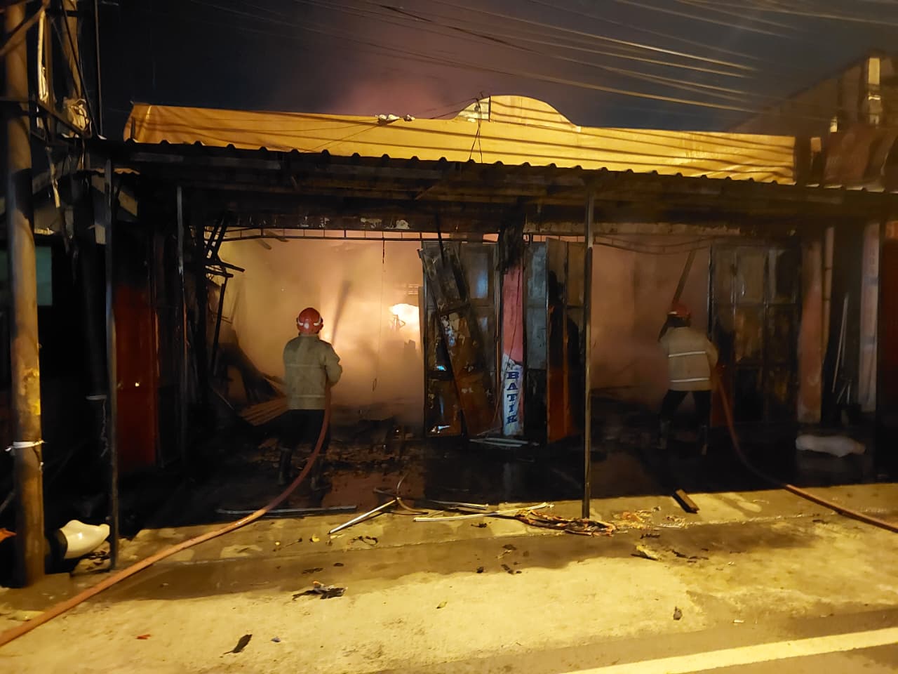 Petugas Damkar Kabupaten Gresik saat memadamkan kebakaran toko pakaian dan rumah di Jalan Bringkang, Desa Bringkang, Kecamatan Menganti, Gresik.