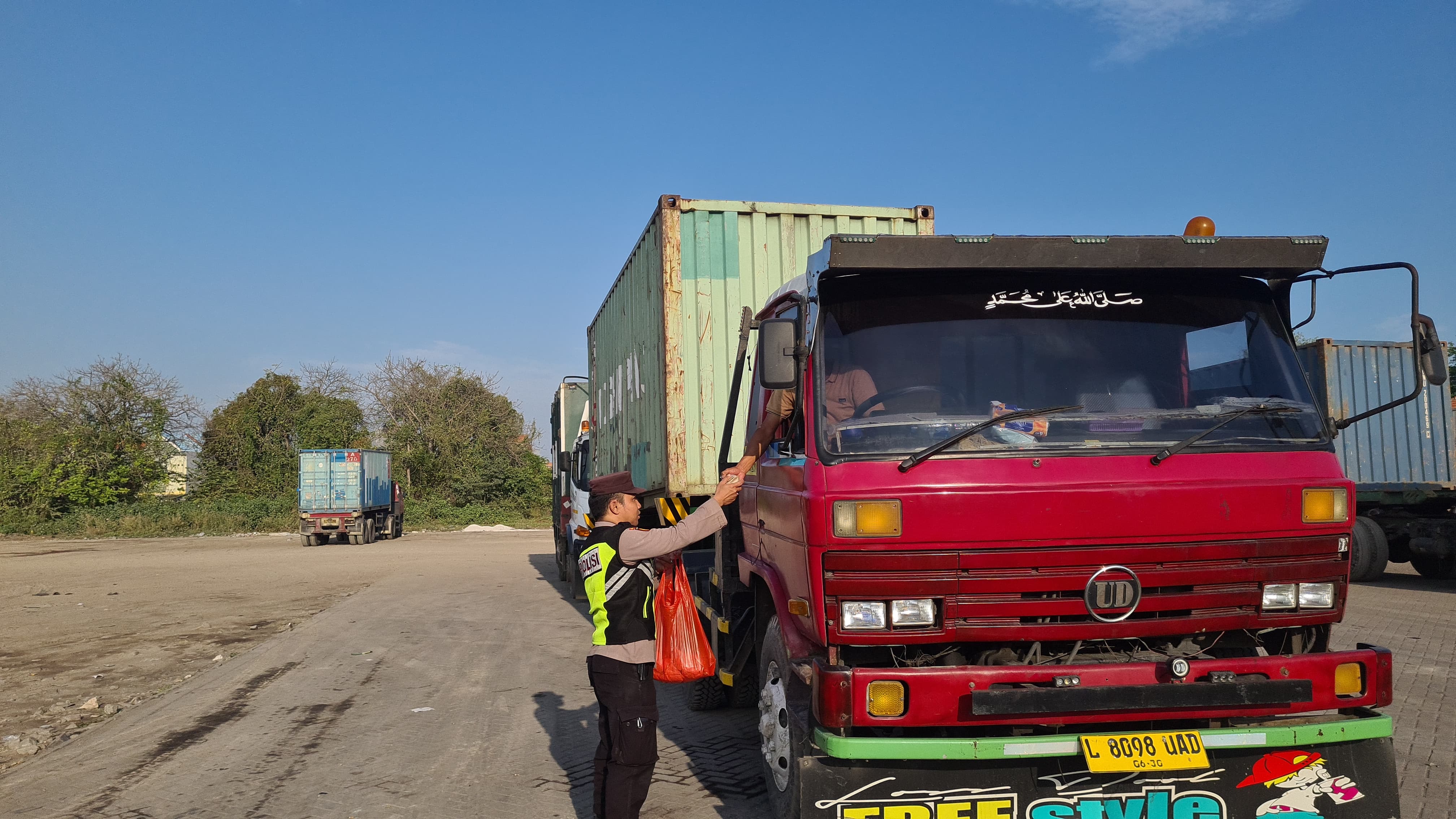 BAGIKAN NASI : Anggota Polsek Sidayu saat membagikan nasi bungkus untuk Sopir truk yang tertib aturan dan tidak melanggar jam operasional melintas.