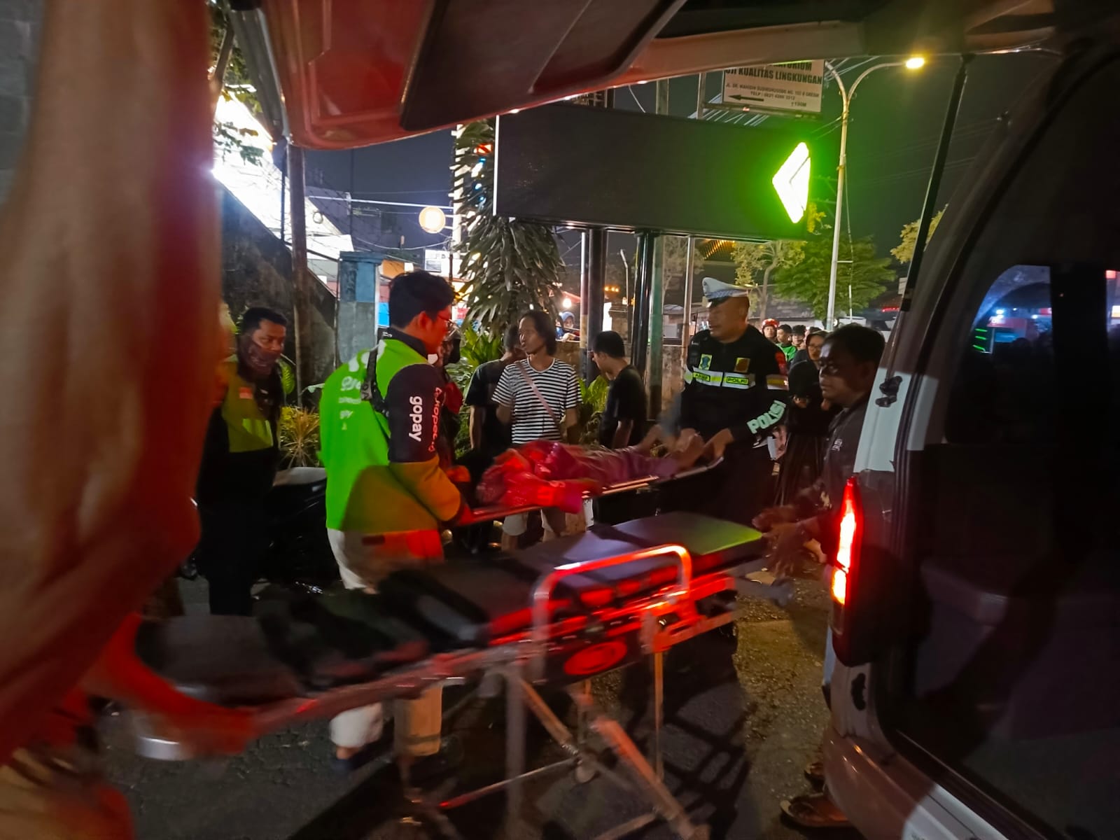 EVAKAUSI : Pengendara Ojol, Warga, dan anggota Satlantas Polres Gresik saat mengevakuasi korban kecelakaan di sekitar Jalan Dr. Wahidin Sudirohusodo, Kecamatan, Kebomas, Gresik.