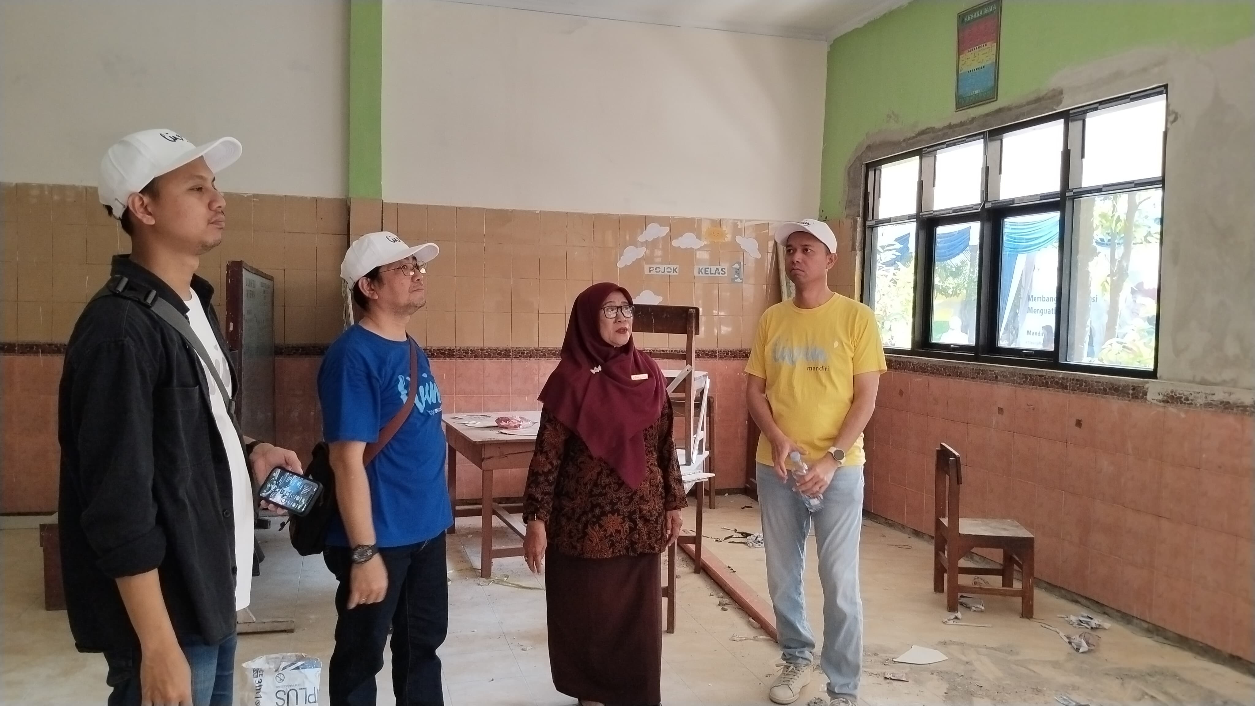 Vice President Bank Mandiri Area Gresik Rizky David Paulus (kaos kuning) didampingi Kepala SDN 06 Babat Hj Agustina memantau langsung proses renovasi salah satu ruang kelas.
