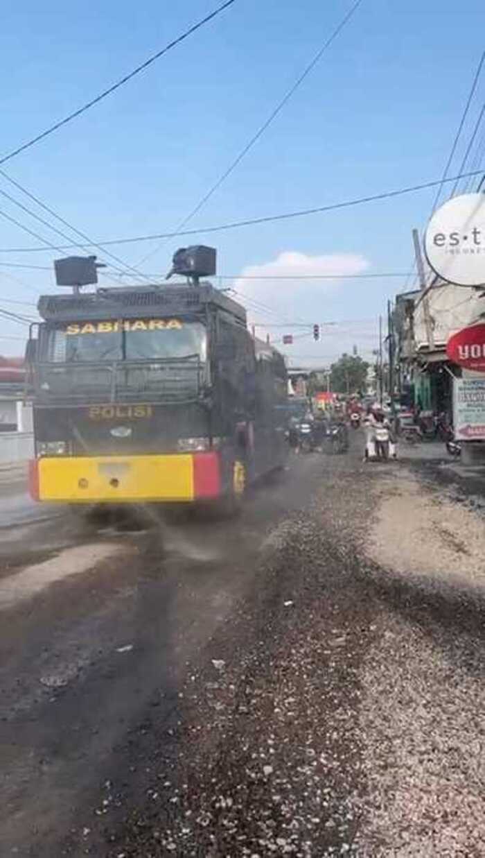 DISEMPROT : Anggota Sat Samapta Polres Gresik saat melakukan penyemprotan Jalan berdebu Imbas Pelebaran Jalan Yosowilangun - Suci menggunakan mobil water Cannon