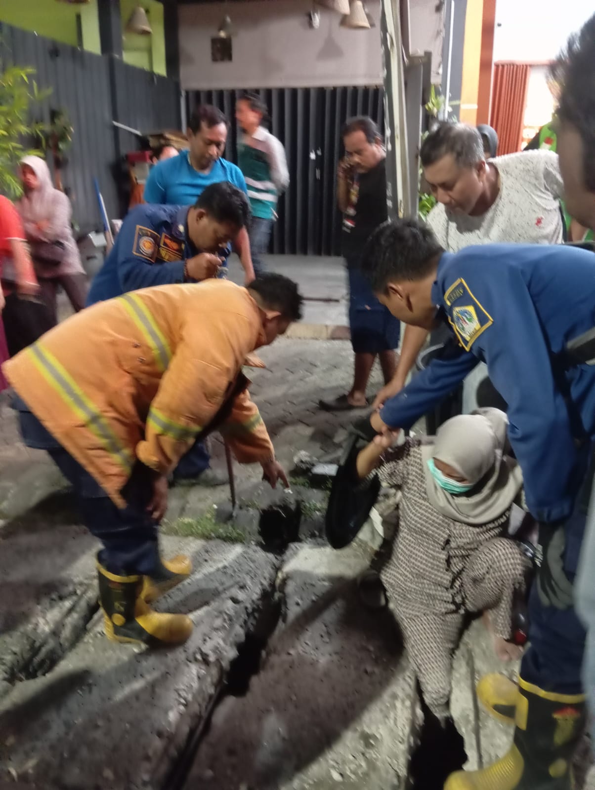 TERPEROSOK : Petugas Damkarla Gresik saat membantu seorang warga Yosowilangun Terperosok ke dalam selokan di di Jalan Kalimantan No. 28, Desa Yosowilangun, Kecamatan Manyar, Gresik.