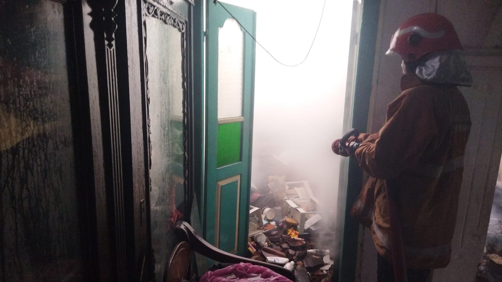 PEMADAMAN: Petugas Damkarla Kabupaten Gresik dibantu warga saat melakukan pemadaman kebakaran sebuah rumah di Jalan Sunan Giri XIII/13 G, Kelurahan Sidomukti, Kecamatan Kebomas, Kabupaten Gresik.