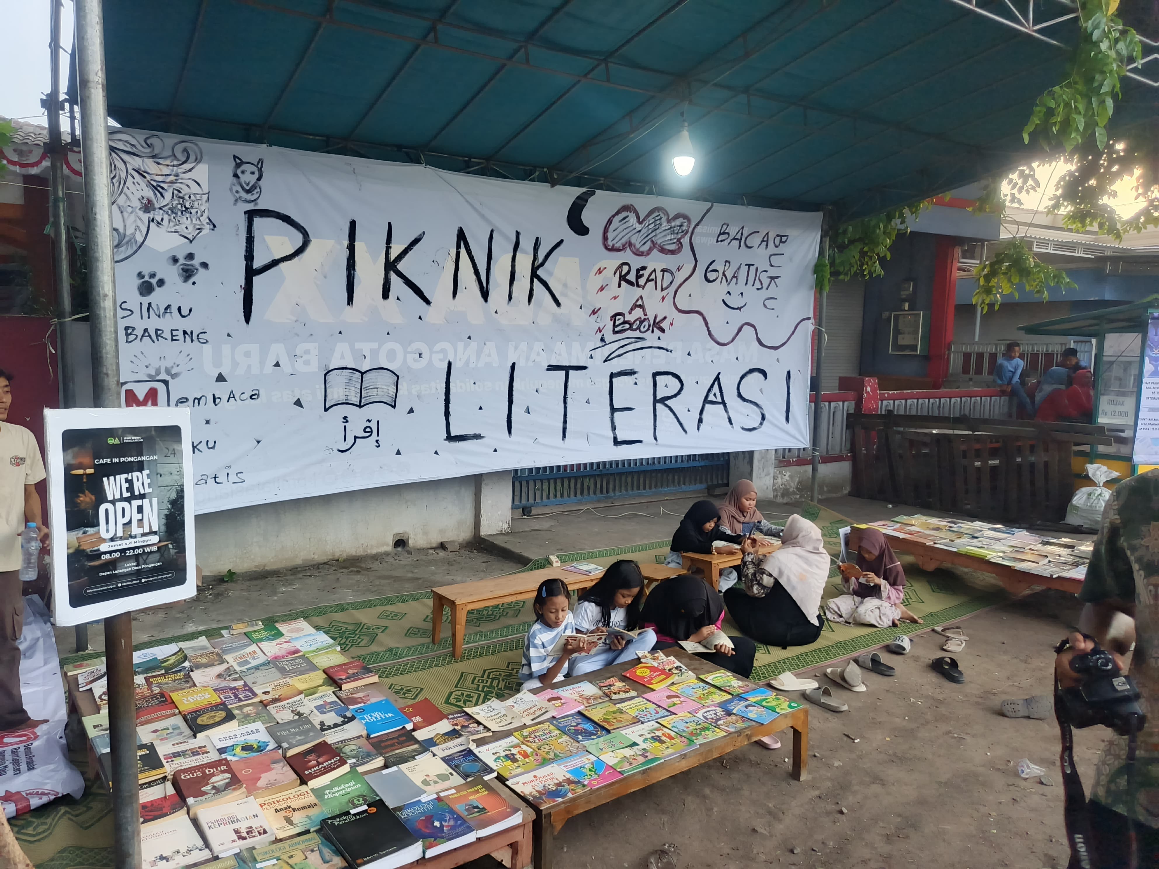 PERPUS: Anak-anak asyik saat membaca buku di Perpustakaan Berjalan yang didirikan mahasiswa PMII dan Pemuda Pongangan di depan Balai Desa.