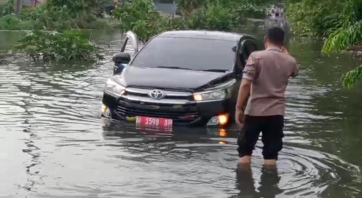 DIEVAKUASI : Anggota Polsek Driyorejo saat melakukan evakuasi mobil Kepala Dinas Perpusip Kabupaten Gresik saat terjebak genangan air banjir di Jalan Mutiara Perumnas Kota Baru Driyorejo Desa Petiken.