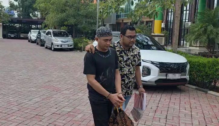 DILIMPAHKAN : Tersangka Ahmad Midhol saat dilimpahkan oleh penyidik Satreskrim Polres Gresik ke kantor Kejari Gresik.