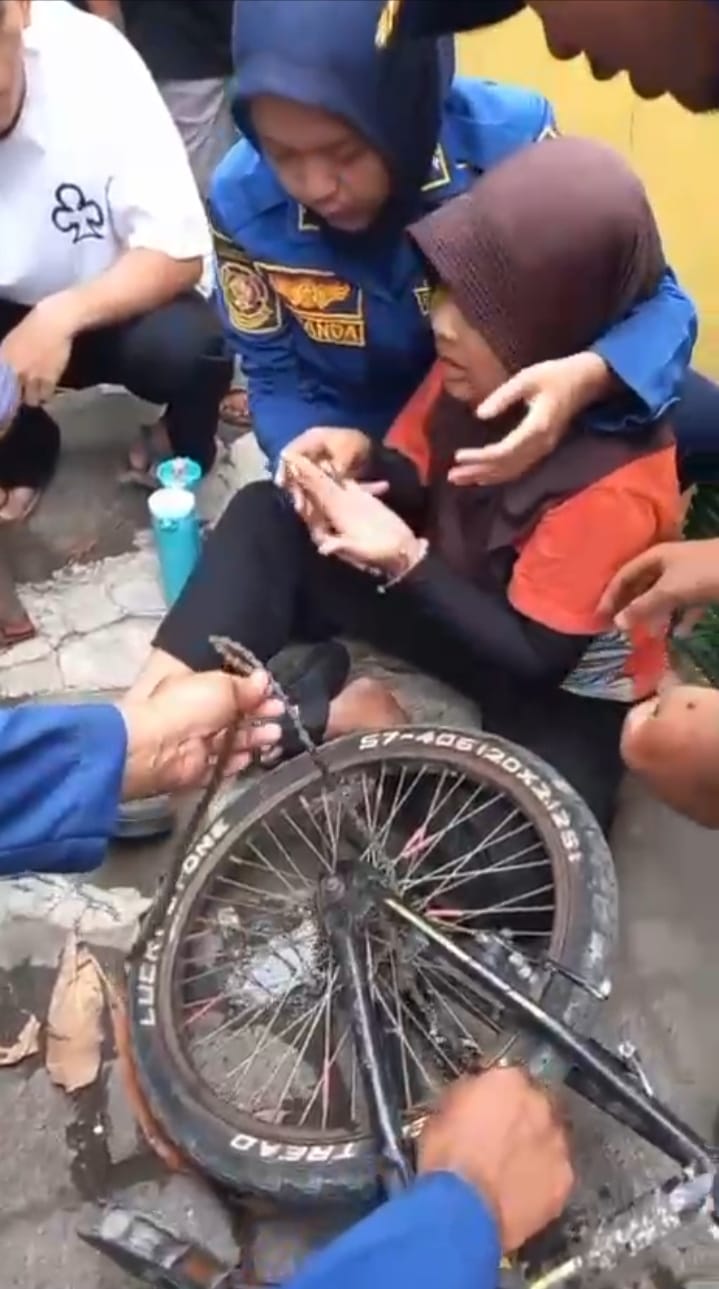 DITOLONG: Petugas Damkar Gresik saat menolong jari tangan anak SD terjepit rantai sepeda.