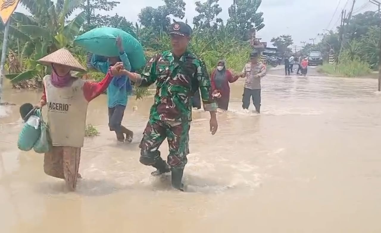 MEMBANTU : Para TNI membantu evakuasi warga yang terdampak banjir.