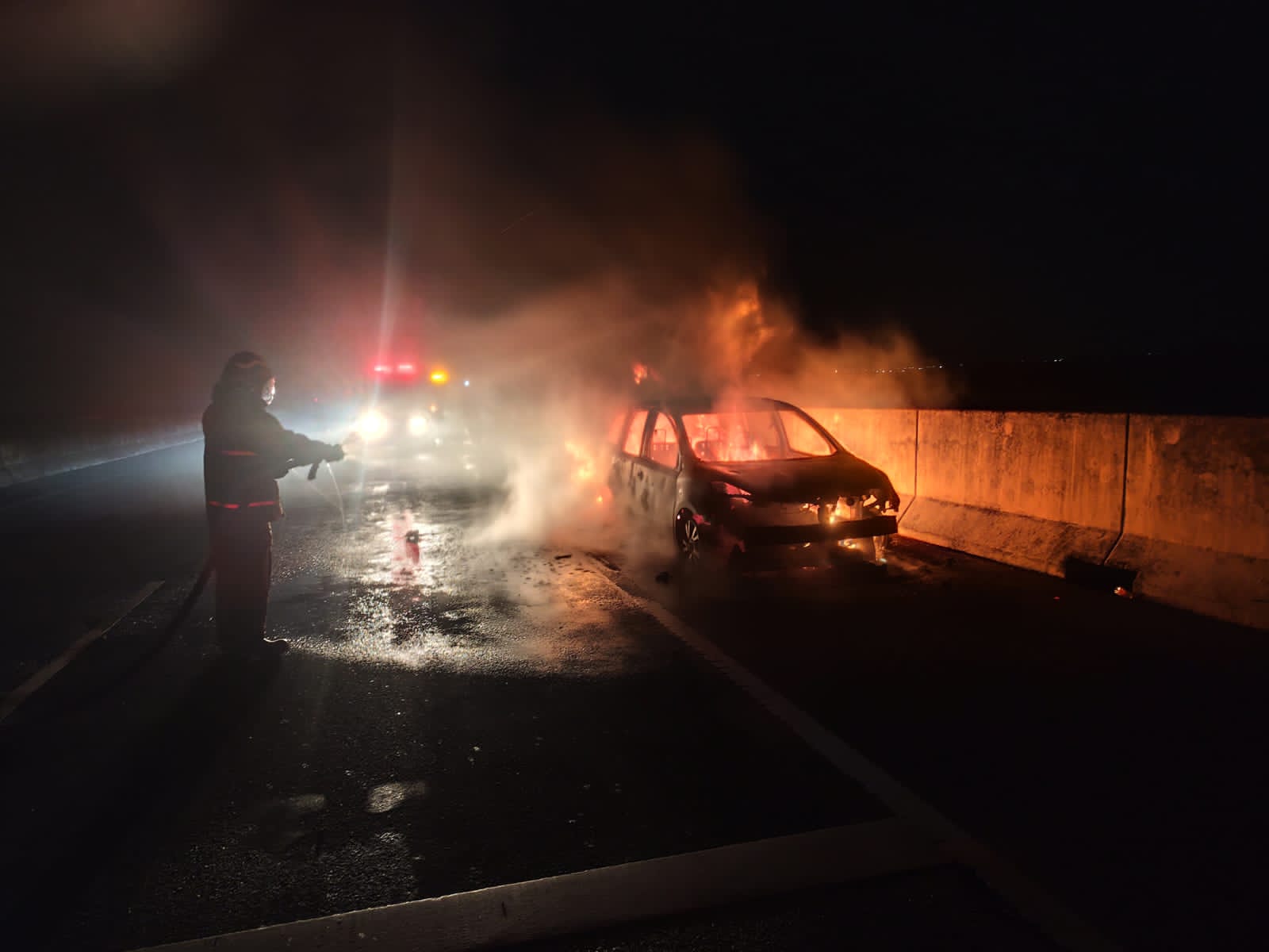 TERBAKAR : Petugas Damkar Gresik saat melakukan pemadaman mobil yang terbakar di jalur KM 27+600 A exit Tol Bunder Gresik.