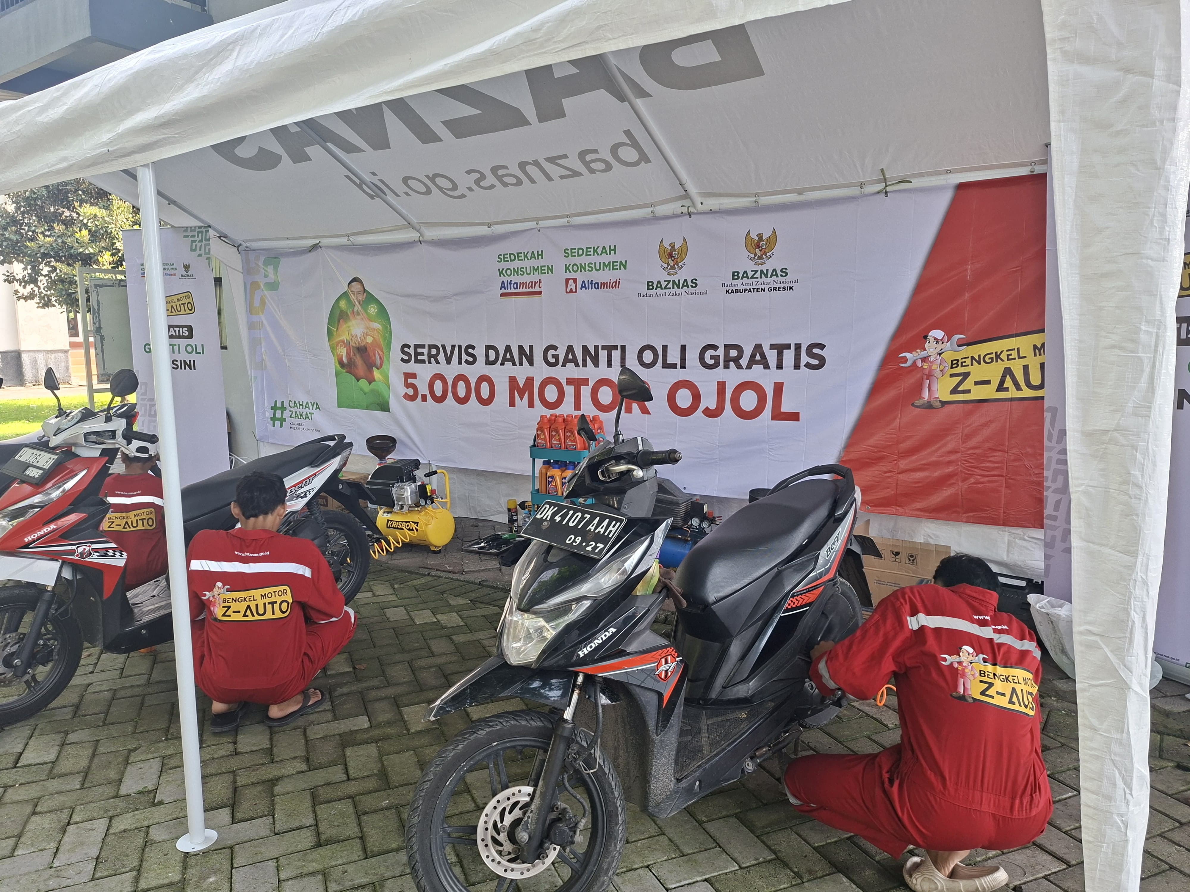 Ratusan Ojol Gresik memanfaatkan program Servis dan Ganti Oli Gratis dari Baznas Gresik, hasil sinergi dengan Baznas RI dan Infak Konsumen minimarket.