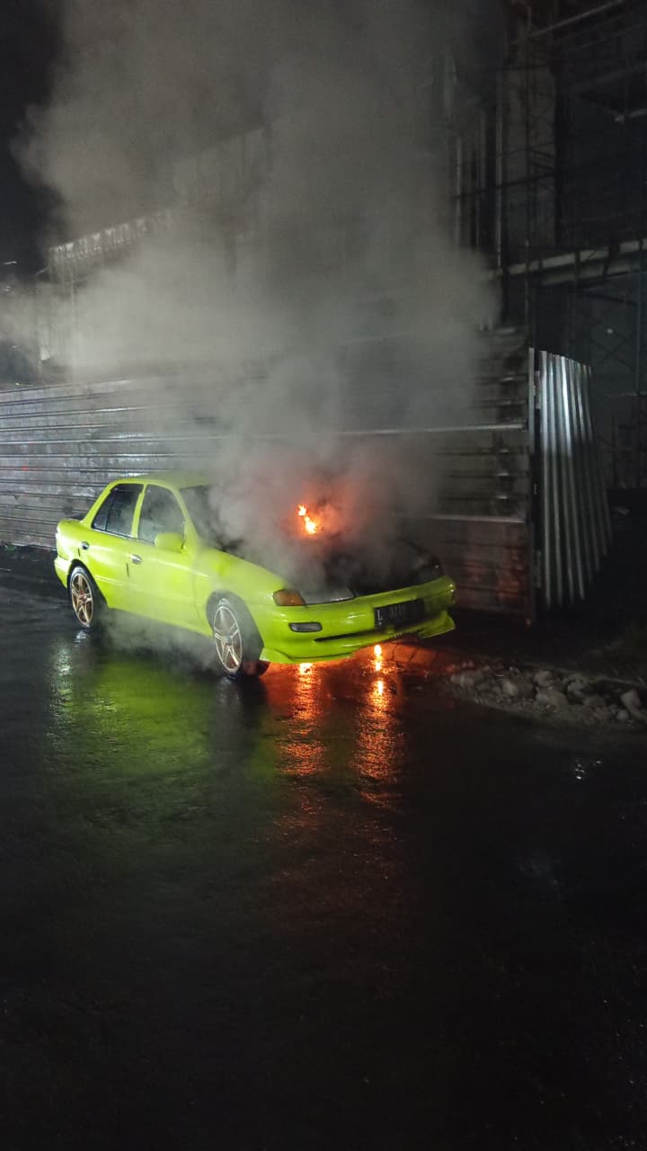 TERBAKAR : Petugas Damkar Gresik saat melakukan pemadaman mobil sedan yang terbakar di Jalan Raya Batu Mulia, Jalan Raya Granit Nila, Kecamatan Driyorejo, Gresik.
