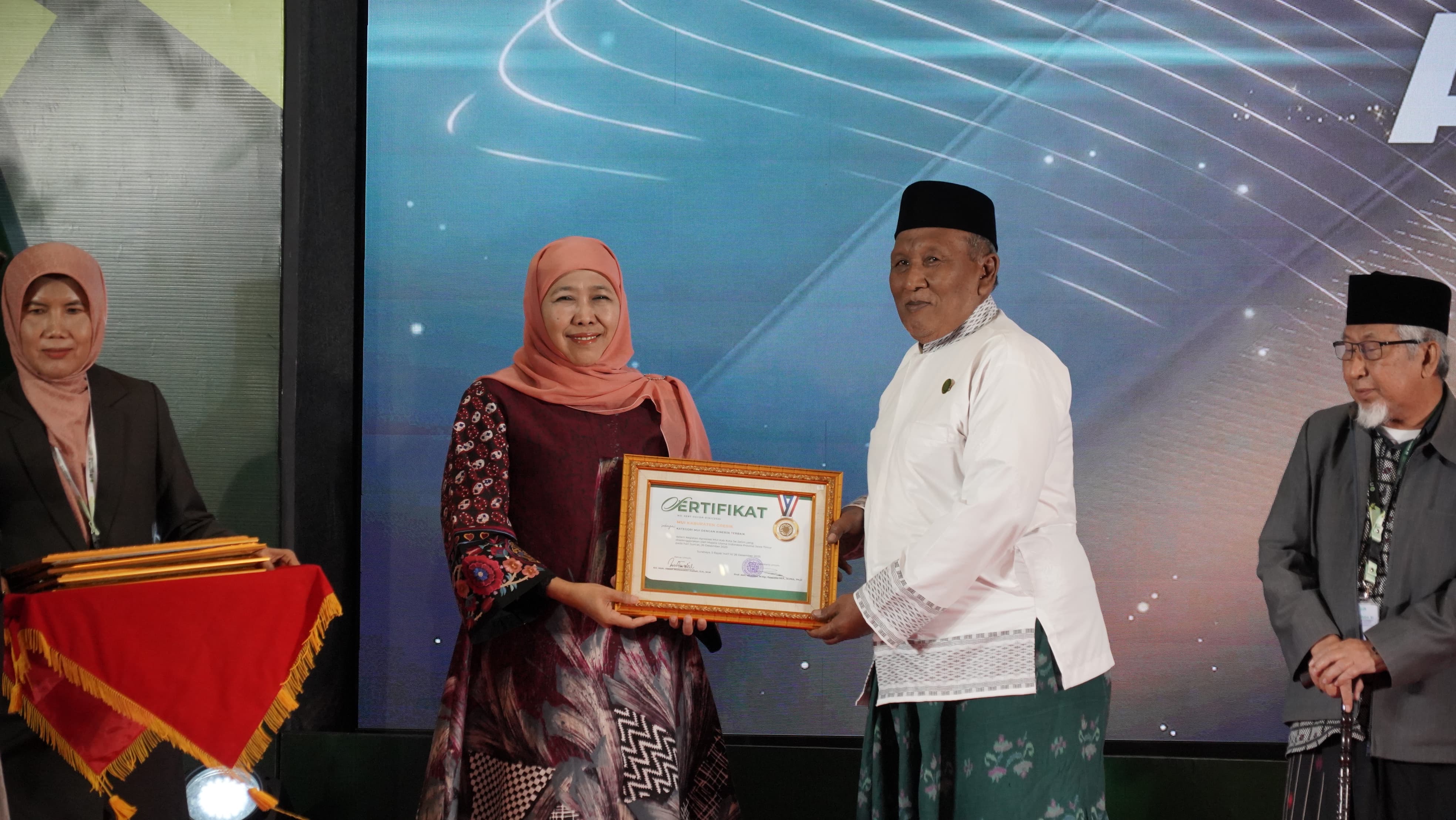 Gubernur Jawa Timur sekaligus Ketua Dewan Pertimbangan MUI Jawa Timur, Dr. (HC) Hj. Khofifah Indar Parawansa menyerahkan penghargaan kepada Ketua Umum MUI Kabupaten Gresik, KH. Ainur Rofiq Thoyyib.