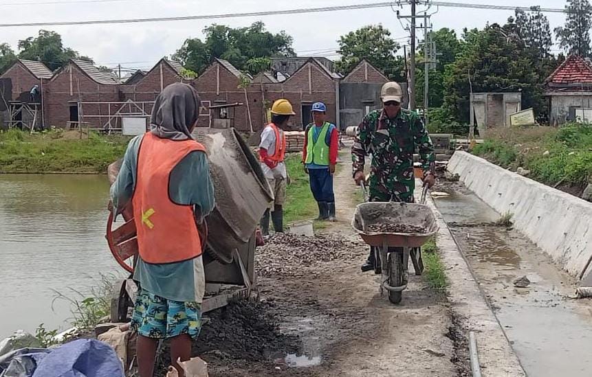 GOTONG ROYONG: Babinsa Koramil Cerme bersama warga melaksanakan karya bakti membangun dinding penahan jalan di poros jalan Dusun Karangan, Desa Kambingan. Langkah ini diambil untuk memperkuat struktur