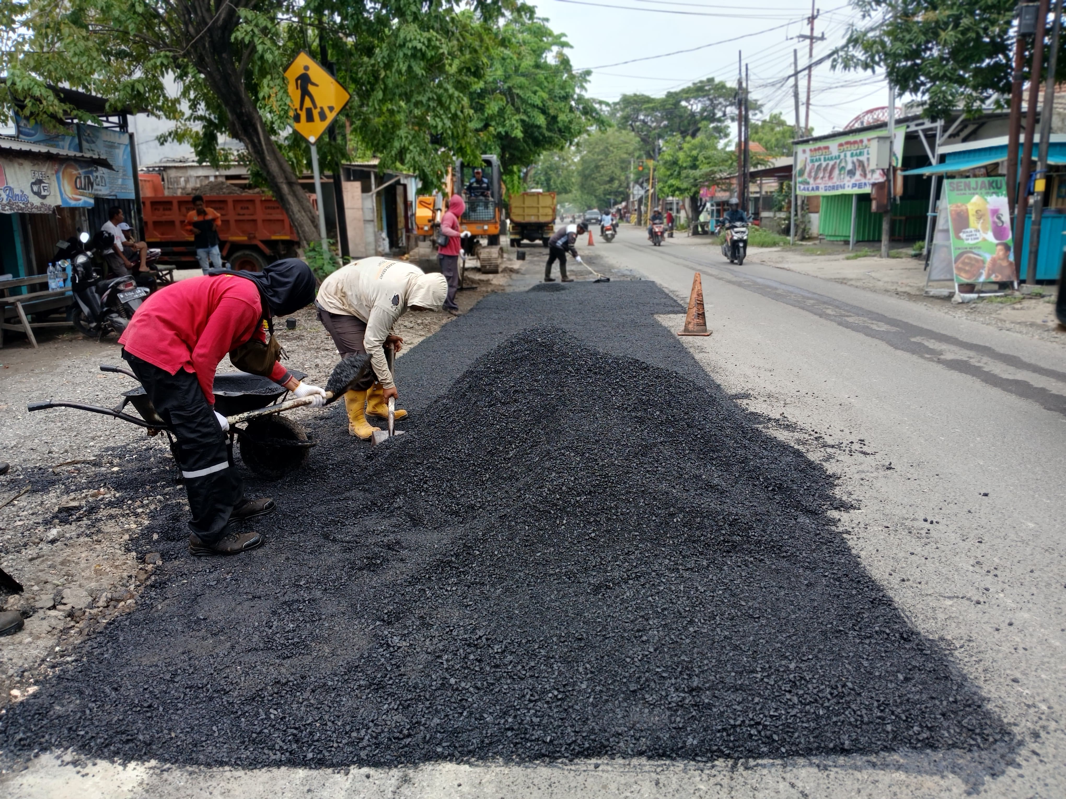 TAMBAL : Personel Tim URC DPUTR Gresik saat melakukan proses tambal sulam menggunakan aspal hotmix di Jalan KH. Syafi&rsquo;i. Sepanjang tahun 2025.