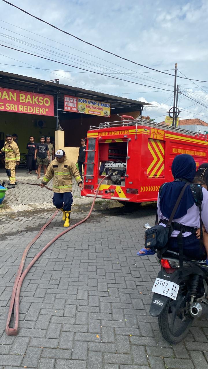 PEMADAMAN : Petugas Damkarla Gresik Pos Driyorejo saat berjibaku memadamkan sisa api pada warung kontainer di Perumahan KBD.