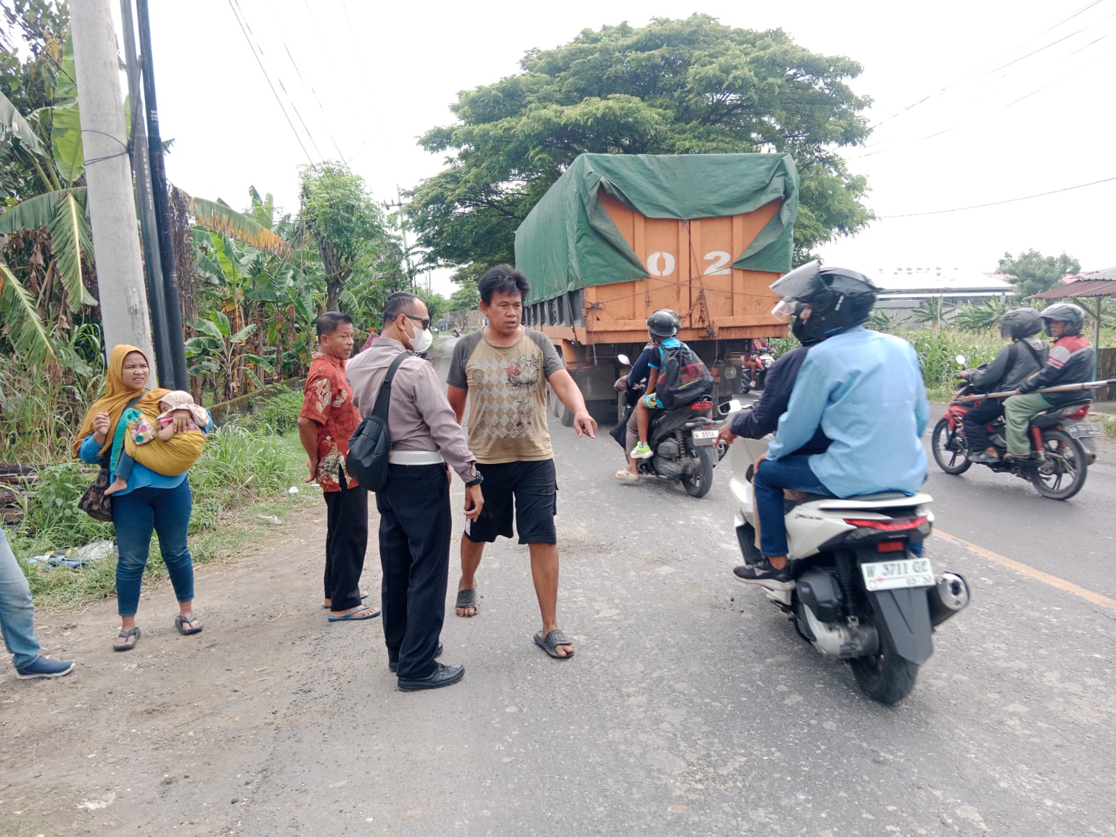 DIEVAKUASI : Anggota Polsek Menganti saat membantu proses evakuasi dan pengamanan lokasi kecelakaan maut di Jalan Raya Domas.