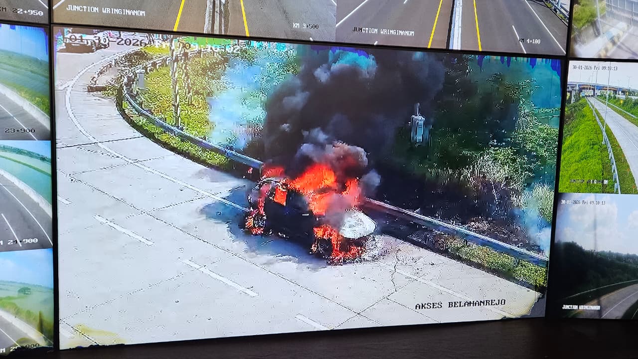 PEMADAMAN : Petugas Damkarla Pos Driyorejo, Gresik saat memadamkan kebaran sebuah  mobil sedan BMW X3 di area pintu masuk tol Belahanrejo, Kecamatan Kedamean, Gresik.
