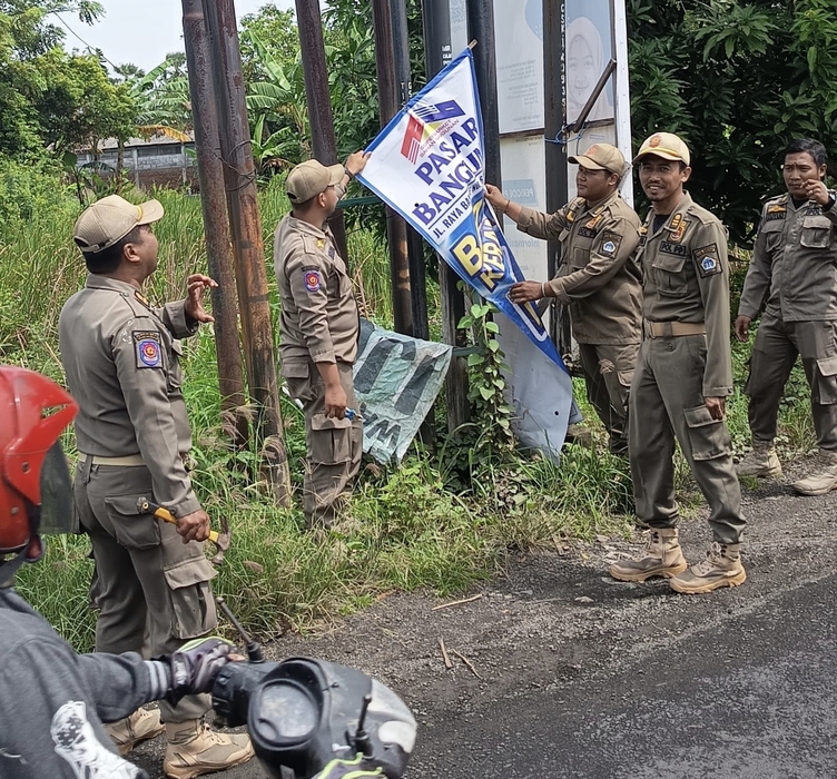 DITERTIBKAN : Anggota Satpol PP Kabupaten Gresik saat mencopiti reklame dan spanduk yang dipasang sembarang di pinggir Jalan Protokol Kabupaten Gresik.