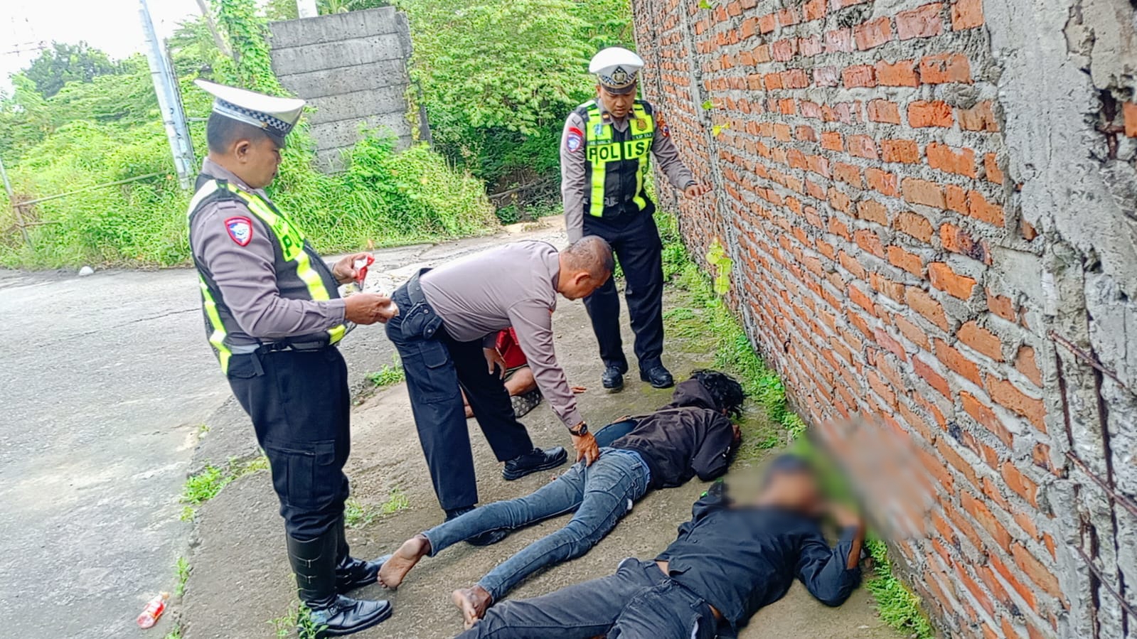 MABUK : Anggota Polsek Driyorejo saat mendatangi tiga pemuda yang tergeletak diduga mabuk arak Bali di pinggir jalan Perumahan Patria Bambe, Kecamatan Driyorejo, Gresik.