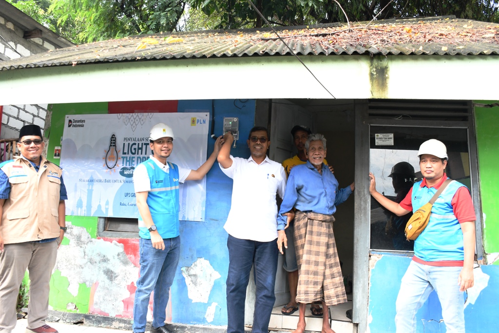 Salikin (baju biru) bersyukur kini rumahnya memiliki sambungan listrik mandiri karena selama 15 tahun  hidup dengan aliran listrik dari tetangga.