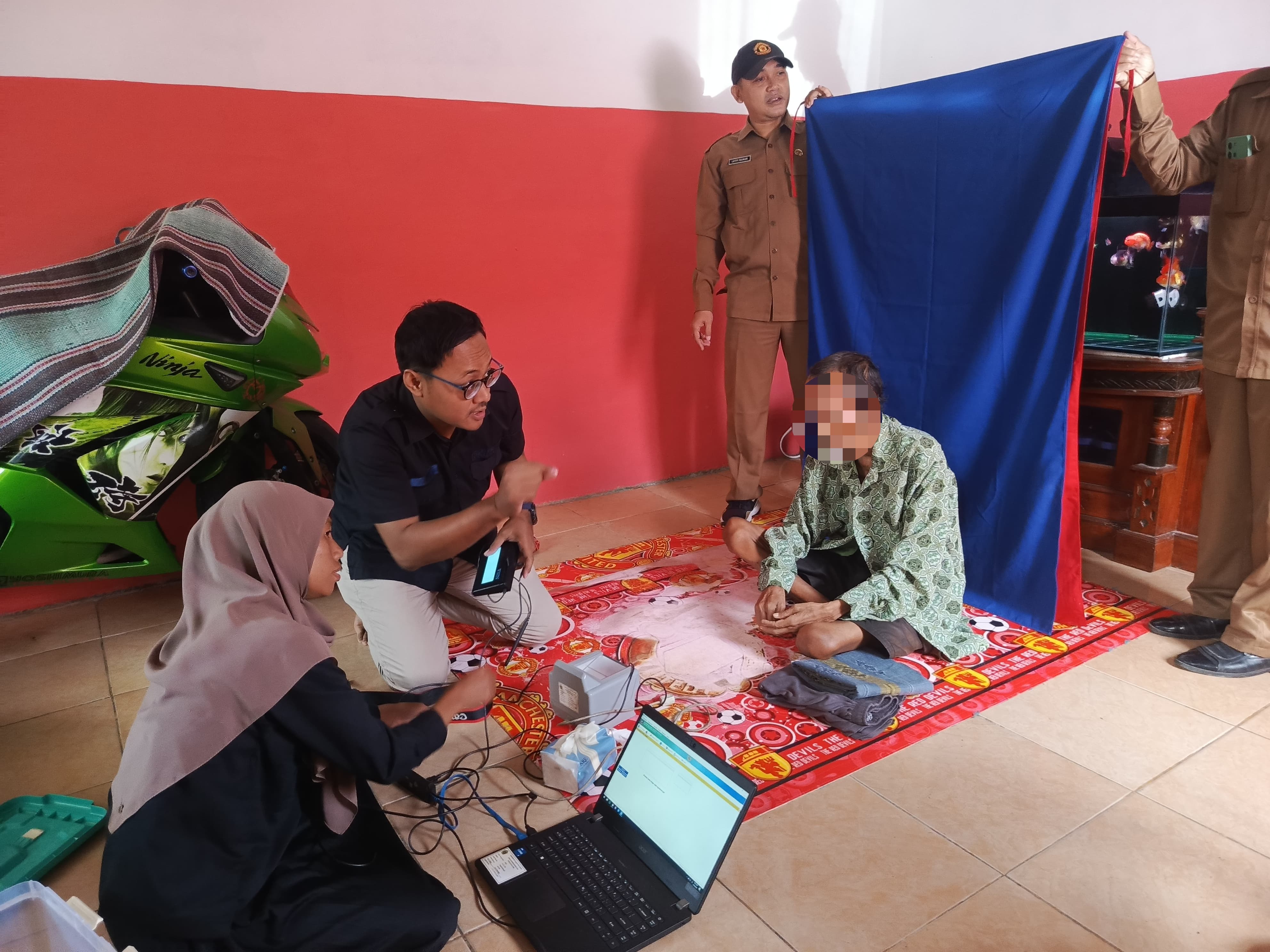JEMPUT BOLA : Petugas Disdukcapil Gresik melakukan perekaman E-KTP langsung dirumah warga.