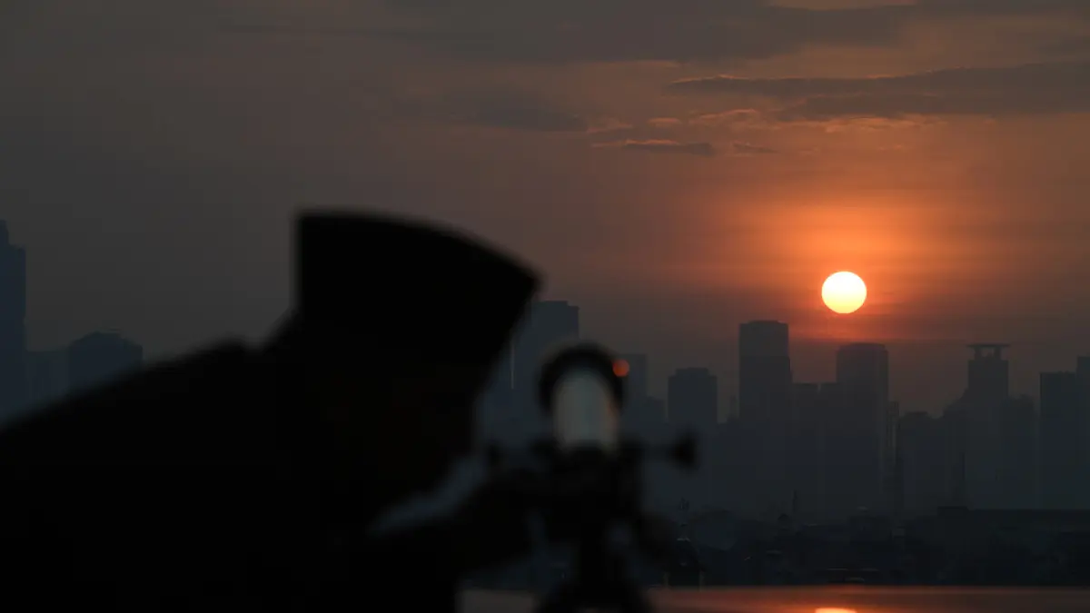 Petugas mengamati matahari terbenam menggunakan teleskop saat melakukan pemantauan hilal.