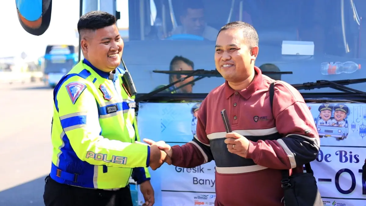 Sigap : Anggota Satlantas Polres Gresik saat mengantar pasutri pemudik asal Situbondo yang tertinggal bus mudik gratis menyusul bus di kawasan Tol Tandes, Surabaya. (Ist/Radar Gresik) 