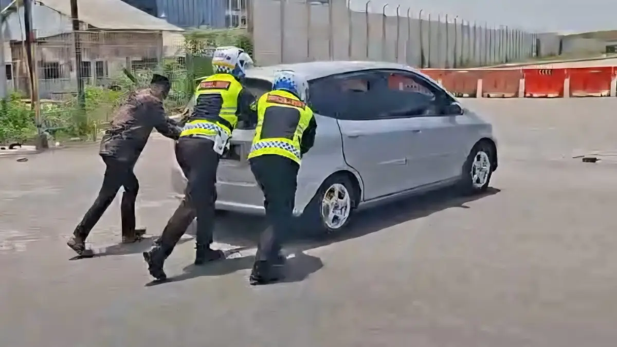 Bantu Dorong : Anggota Satlantas Polres Gresik saat menantu pemudik yang mobilnya mogok di jalan Raya Bungah, Gresik. (Ist/Radar Gresik) 
