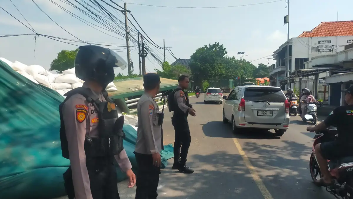 Rem Blong: Anggota Polres Gresik saat mengatur arus lalu lintas di lokasi kecelakaan truk tronton yang menabrak rumah warga.  (Ist/Radar Gresik) 